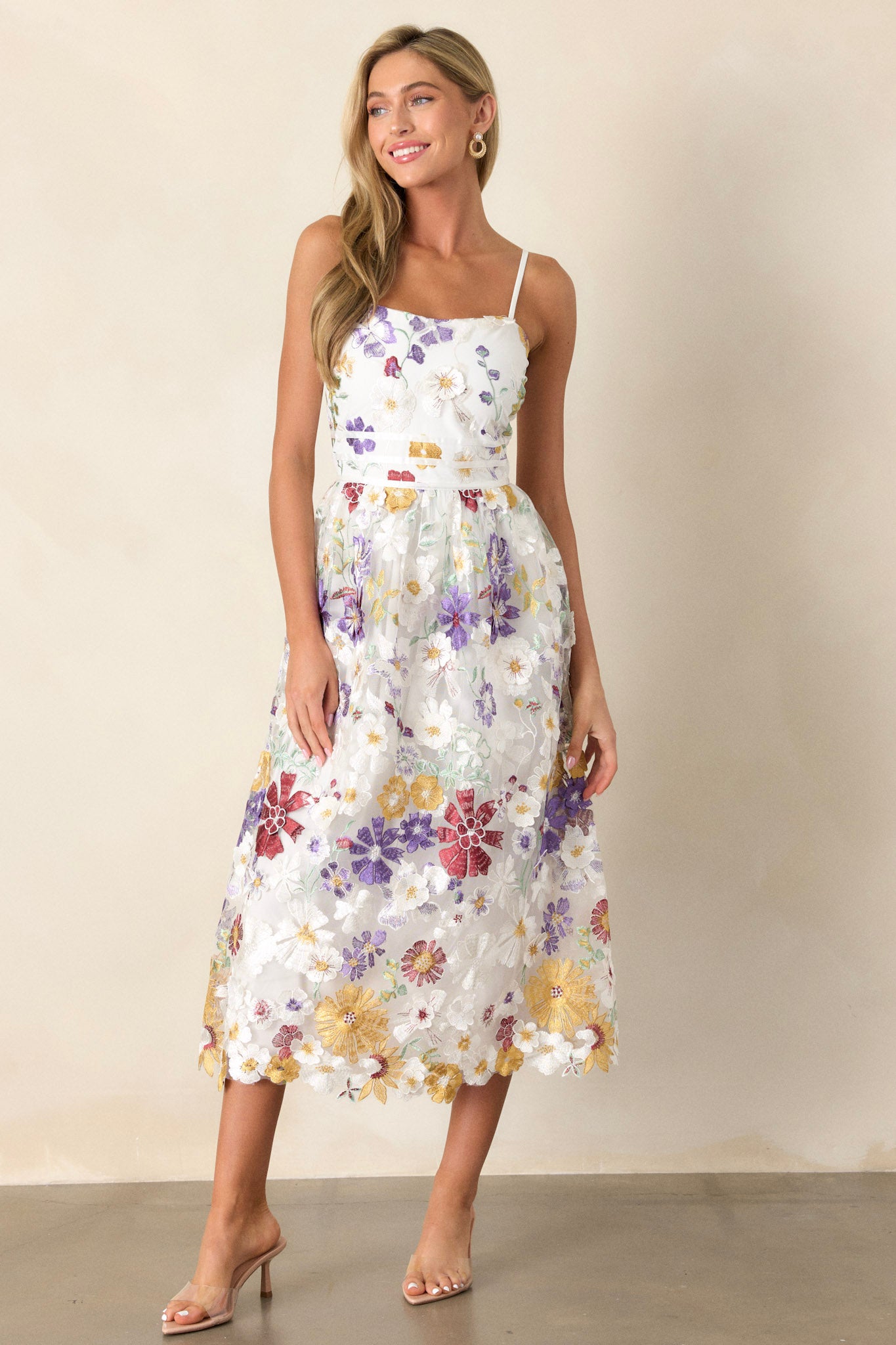 Full length view of this ivory floral dress that features a square neckline, multicolor floral embroidery, a back zipper, and adjustable spaghetti straps.