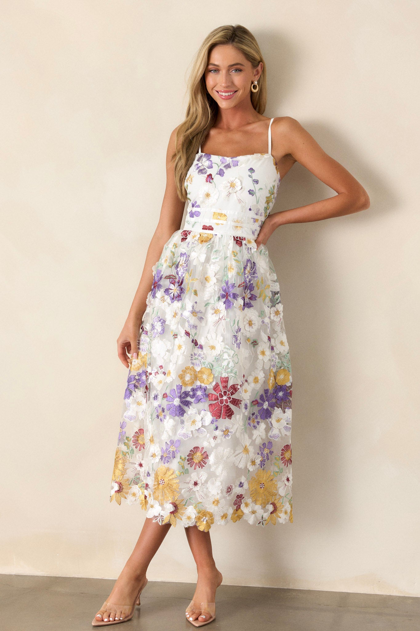 Front angled view of this ivory floral dress featuring a square neckline, multicolor floral embroidery, a back zipper, and adjustable spaghetti straps.&nbsp;