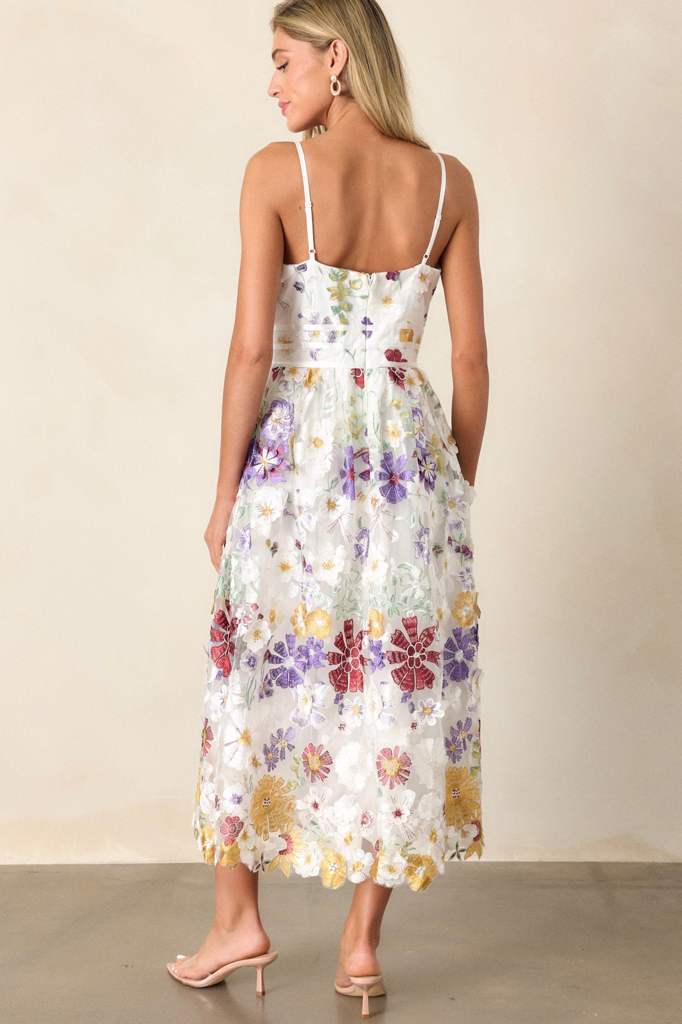 Back view of this ivory floral dress featuring a square neckline, multicolor floral embroidery, a back zipper, and adjustable spaghetti straps.