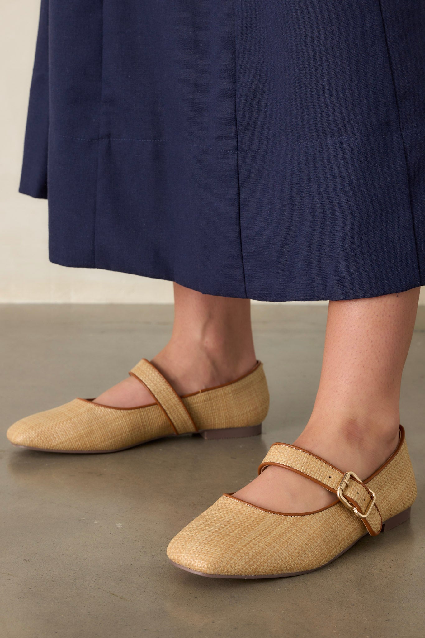 Front view of these natural flats that feature a square toe, a buckle closure, and a brown detailing around edge.