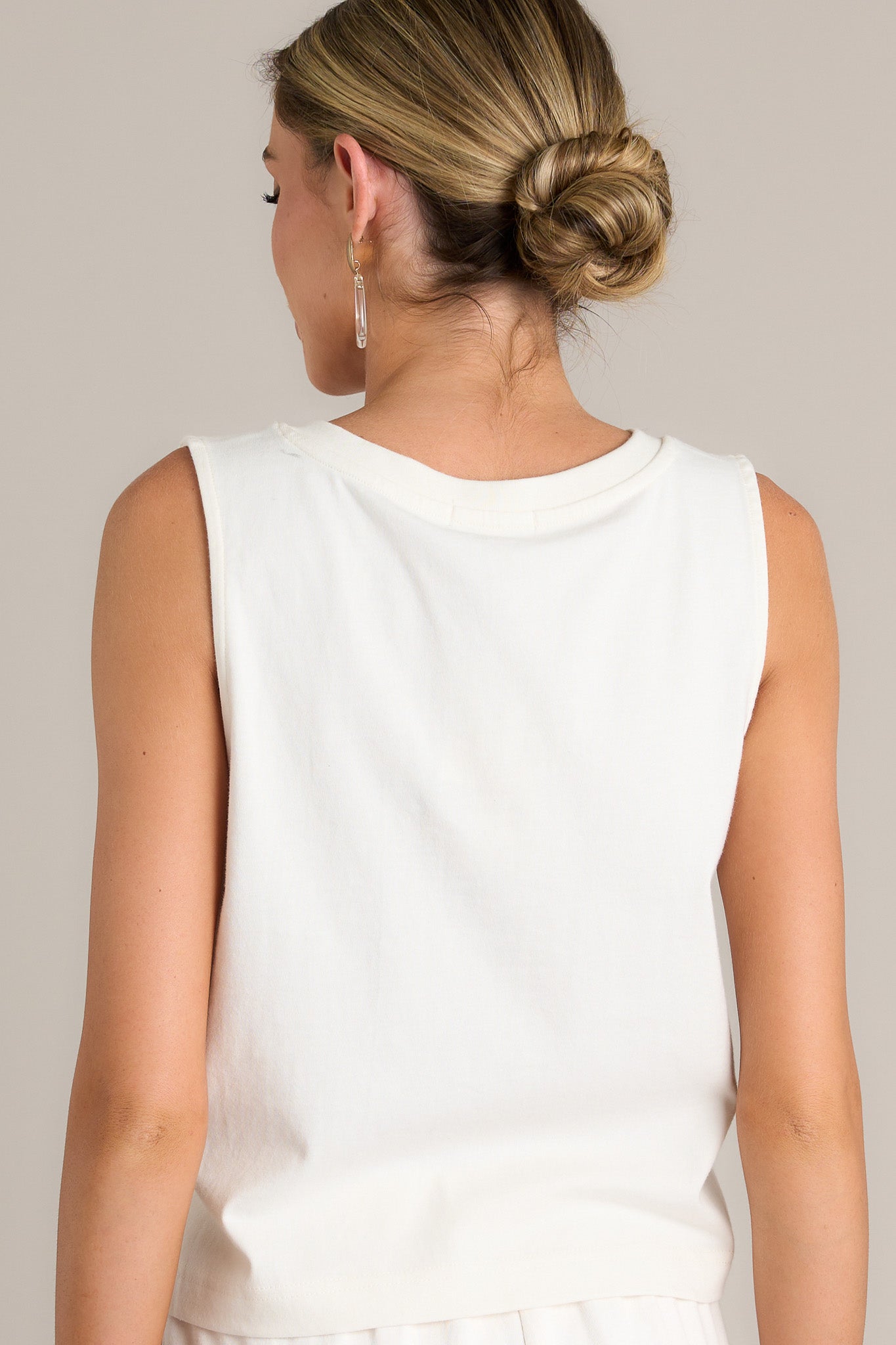 Back view of a white tank highlighting the sleeveless design and overall fit.