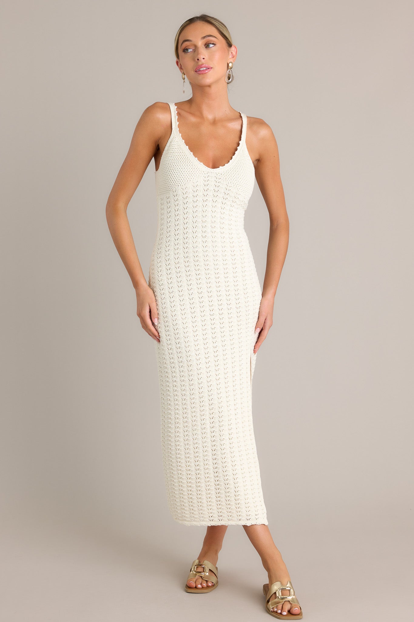 This sandstone midi dress features a v-neckline, thin straps, a unique crochet design, and a side slit.