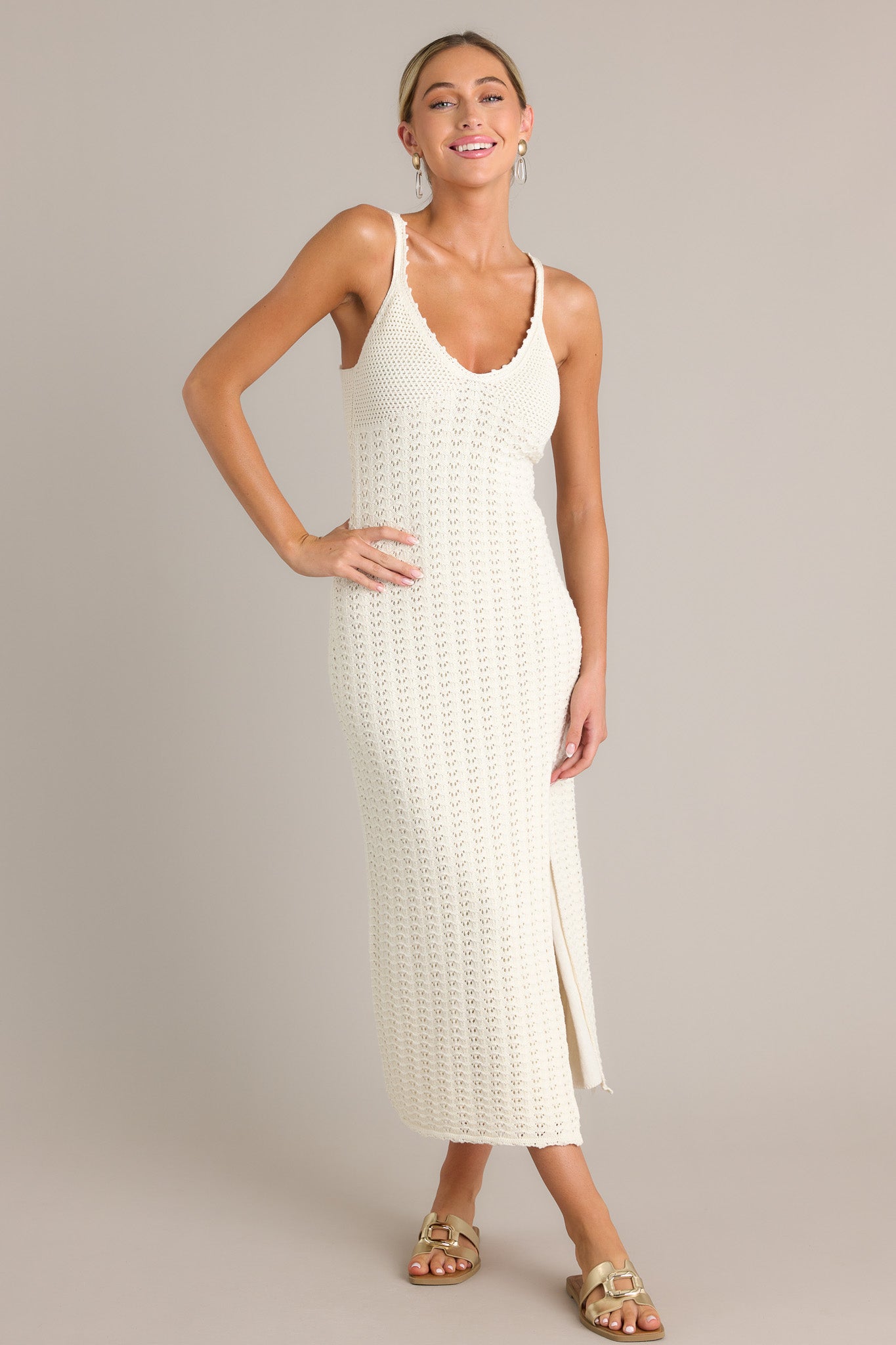 Full view of this sandstone midi dress featuring a v-neckline, thin straps, a unique crochet design, and a side slit.