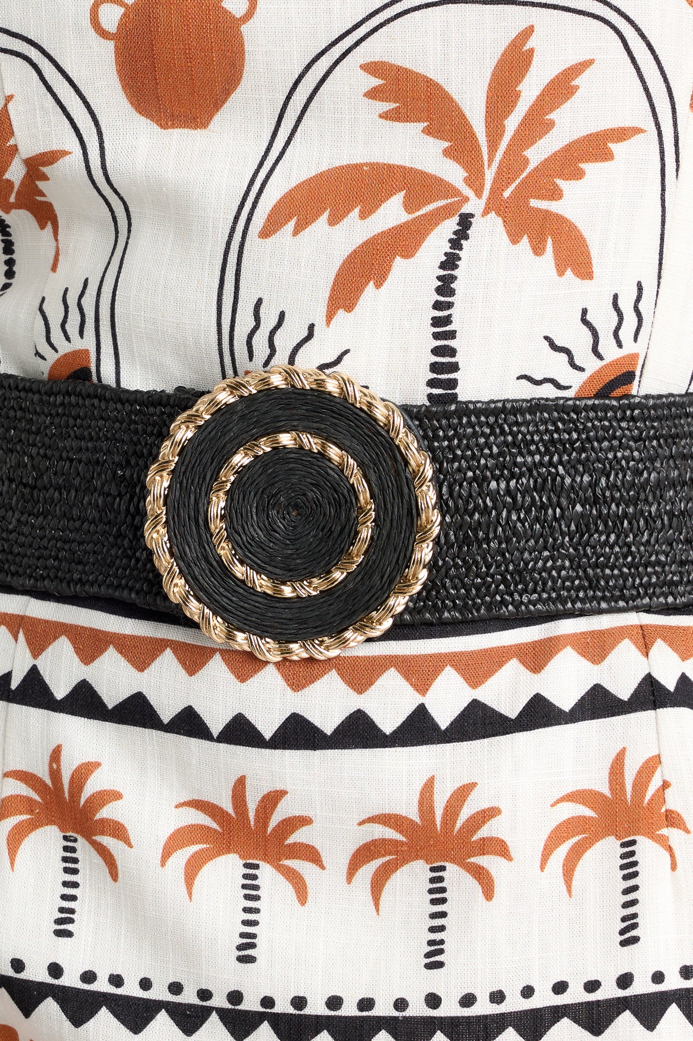 Close up view of this belt featuring gold hardware, an elastic band, a circular design, and a hook and bar closure.