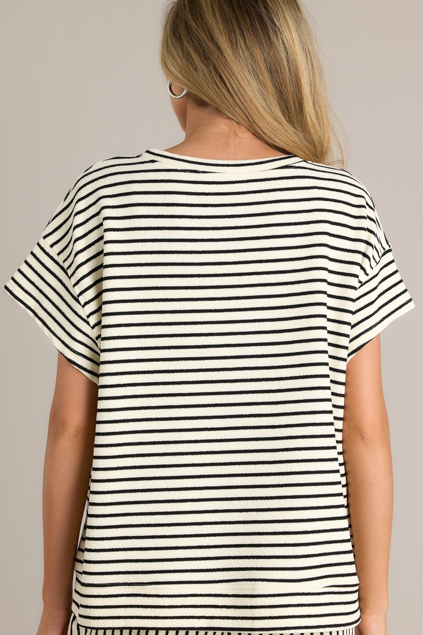 Back view of a black stripe top highlighting the thick textured material, short sleeves, and overall fit.