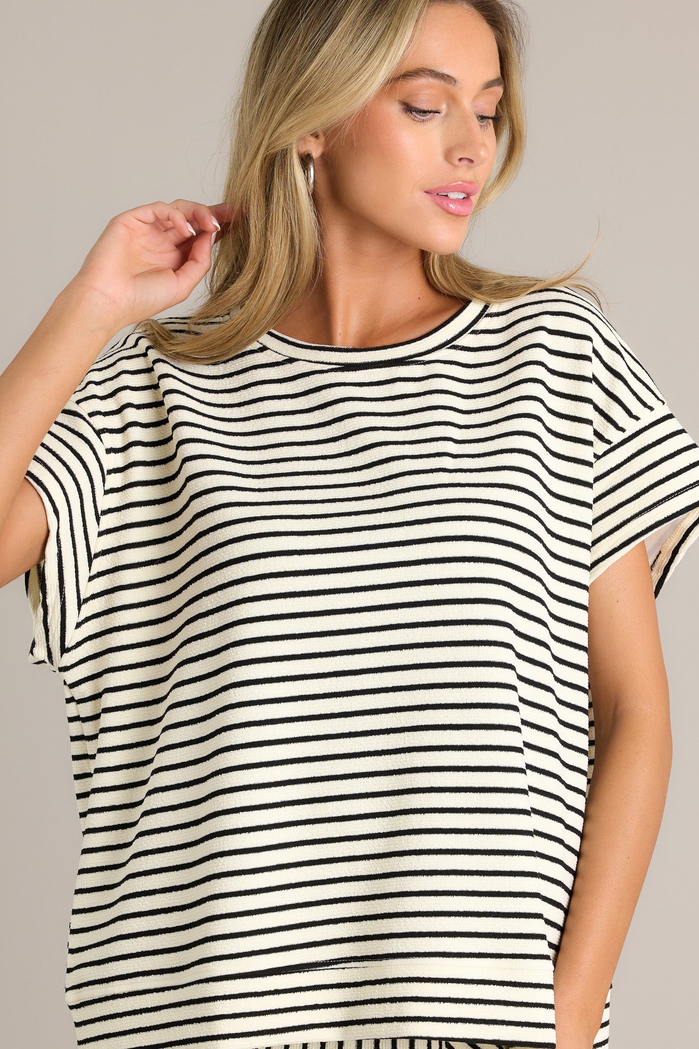 Front view of a black stripe top featuring a crew neckline, a thick textured material, a thick hemline, and short sleeves.