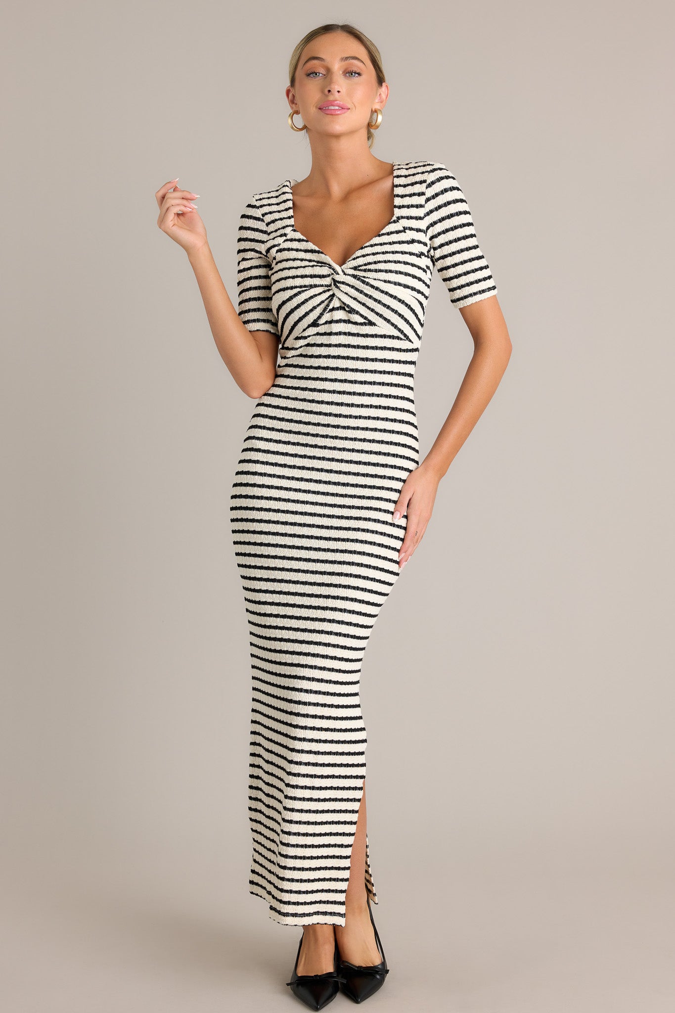 Full view of this black stripe maxi dress featuring a v-neckline, a twisted bust detail, a bodycon fit, a textured fabric, a side slit, and short sleeves.