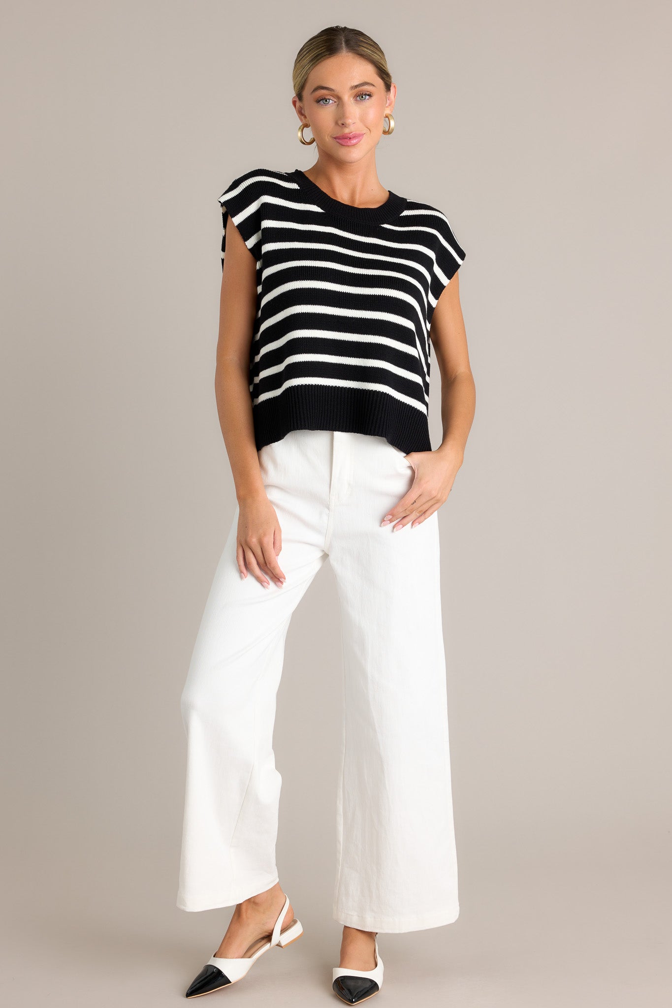 Full view of this black sweater top featuring a ribbed crew neckline, horizontal white stripes, a split ribbed hemline, and short sleeves.