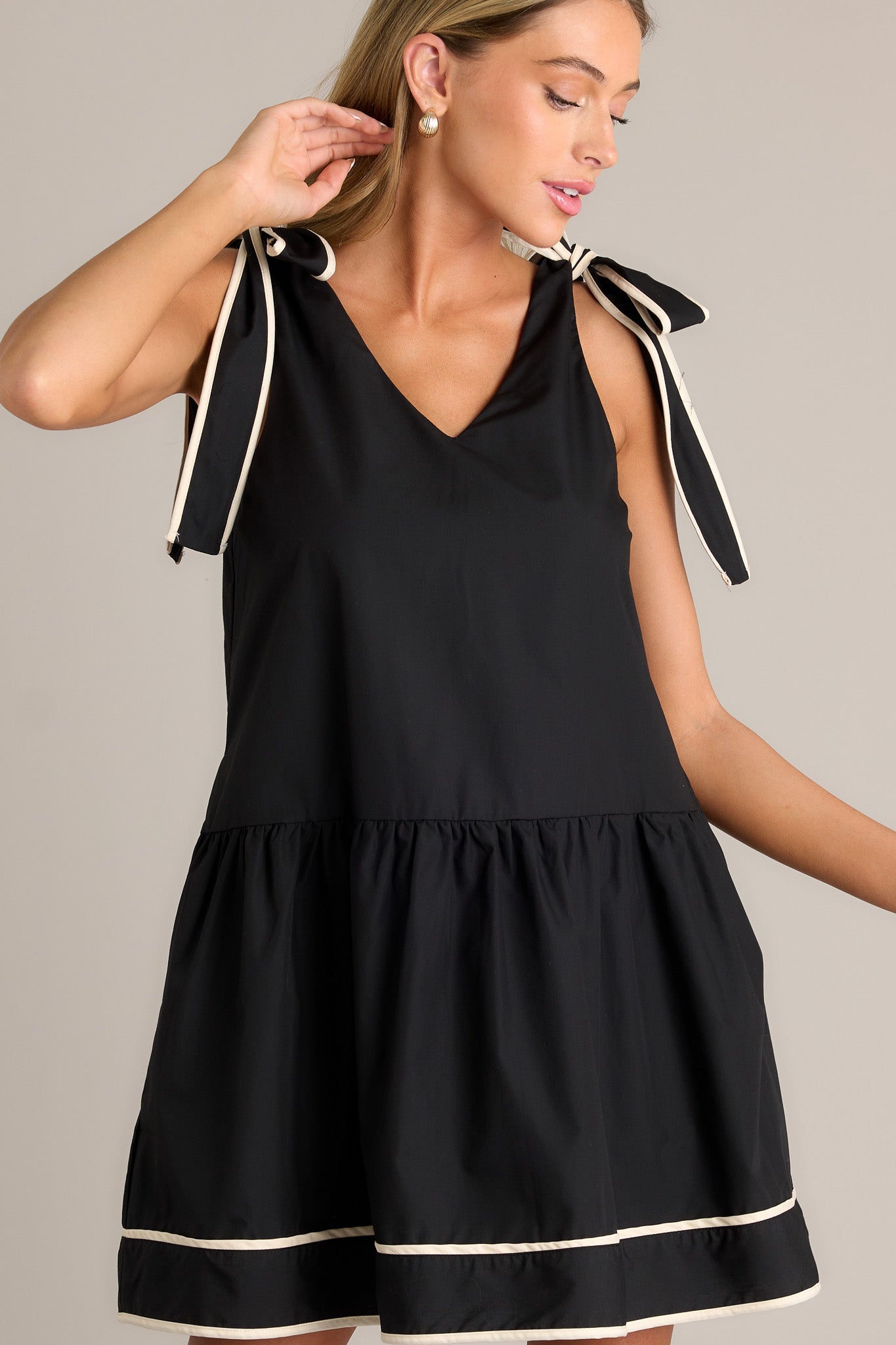 Detailed view of the black mini dress emphasizing the single tier and the thick self-tie shoulder straps.