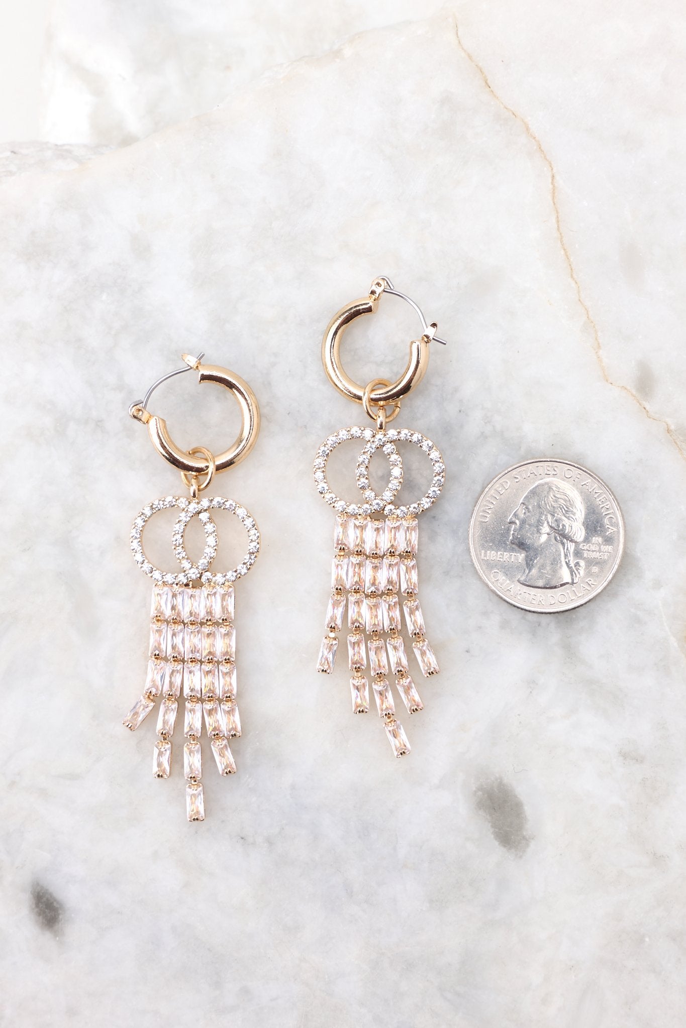 Size comparison of these earrings that feature a round hoop, rhinestone embellishments, and a hinged hoop closure.