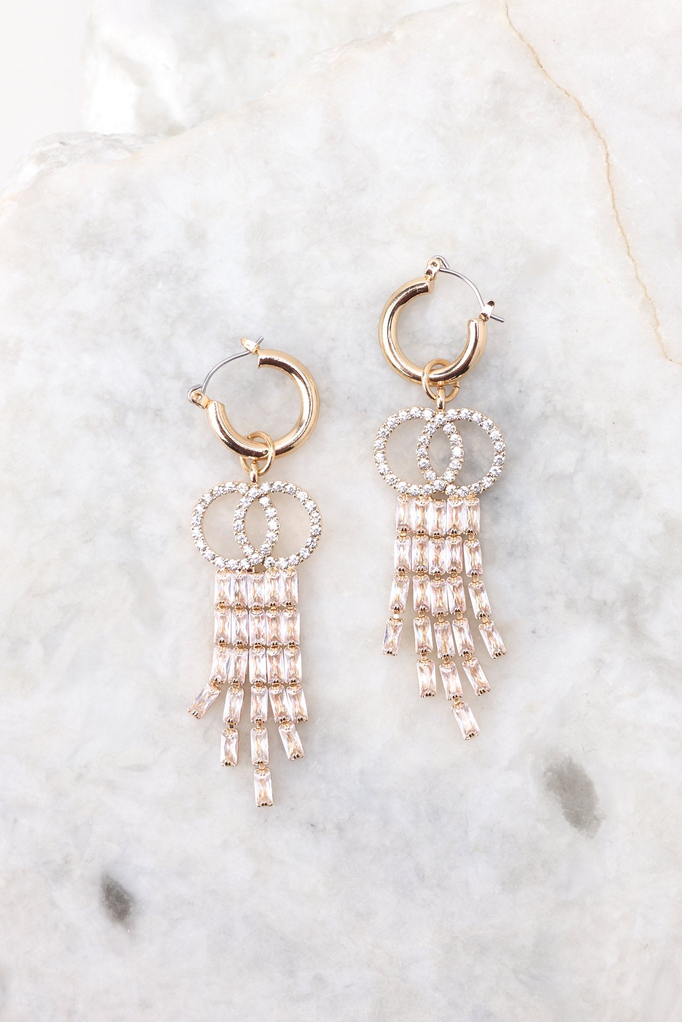 Overhead view of these earrings that feature a round hoop, rhinestone embellishments, and a hinged hoop closure.