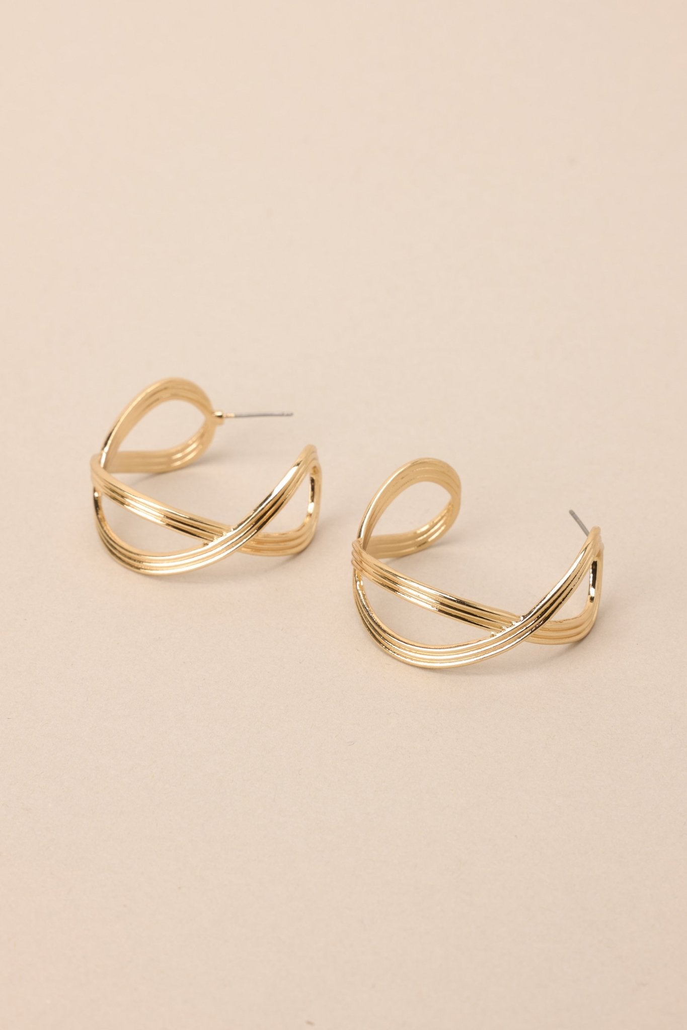 Overhead angled view of these gold hoop earrings that feature gold hardware, a textured and twisted design, and secure post backings.