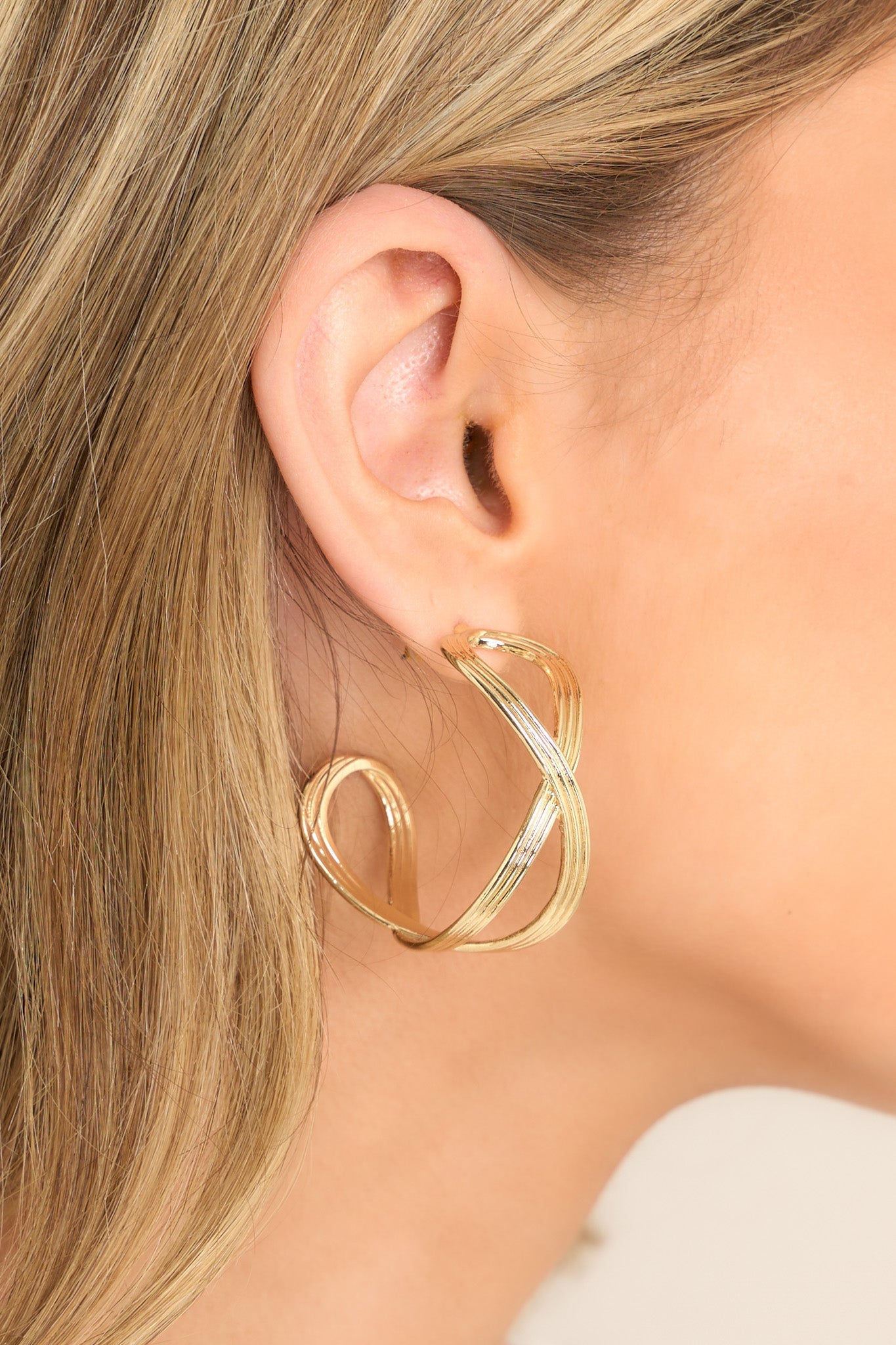 These gold hoop earrings feature gold hardware, a textured and twisted design, and secure post backings.
