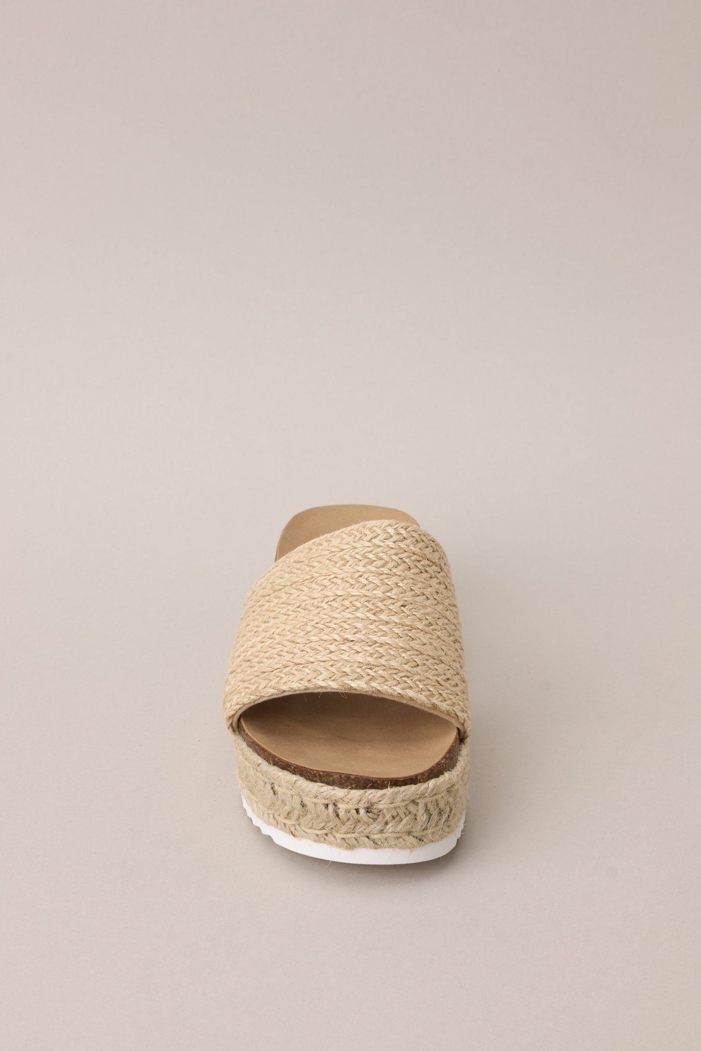 Front view of these natural sandals with rounded toe, slip-on design, strap over foot, espadrille detailing, textured sole.