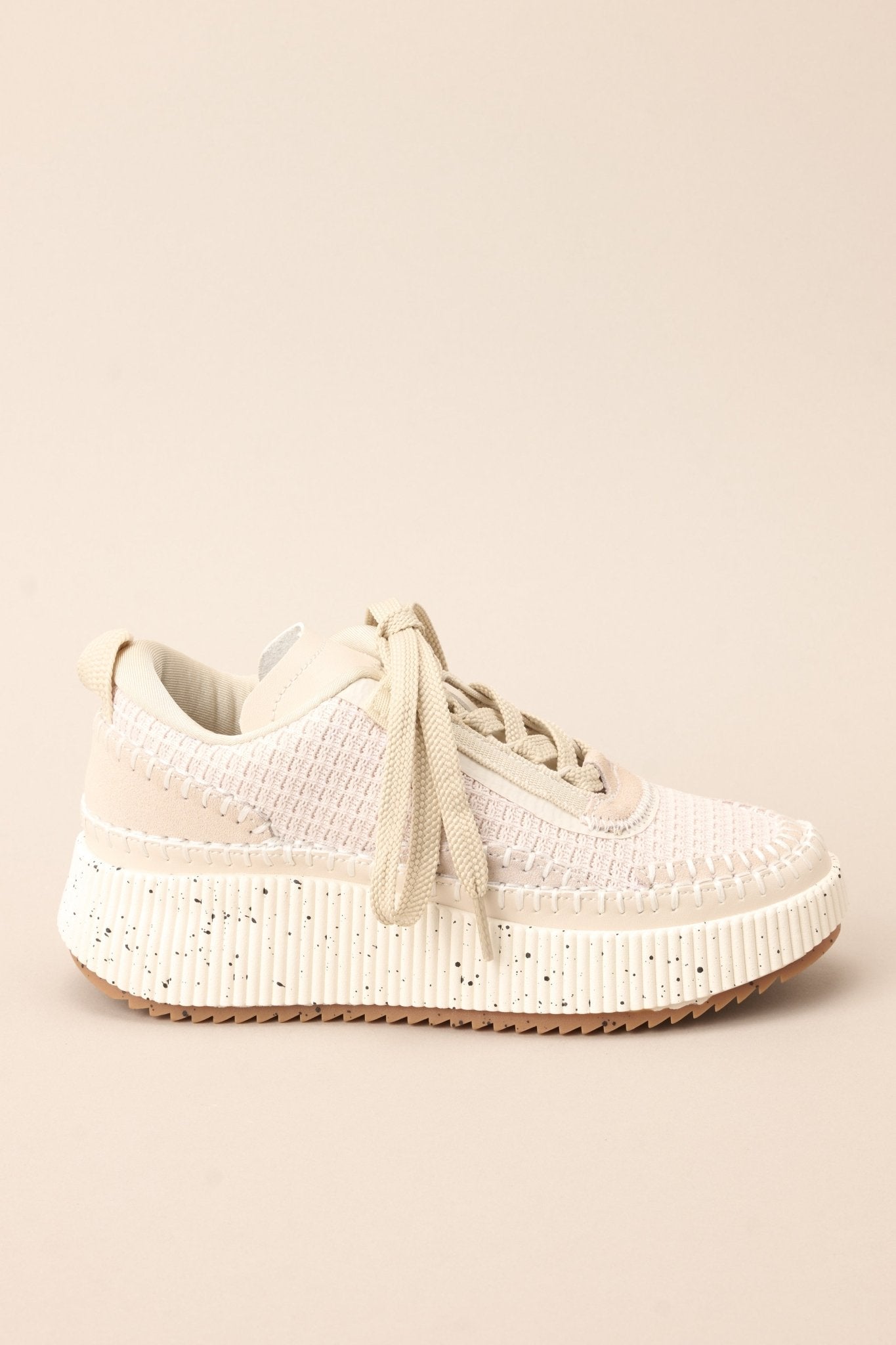 Side view of these beige sneakers with rounded toe, functional laces, knitted detailing, comfortable fit, thick speckled sole.
