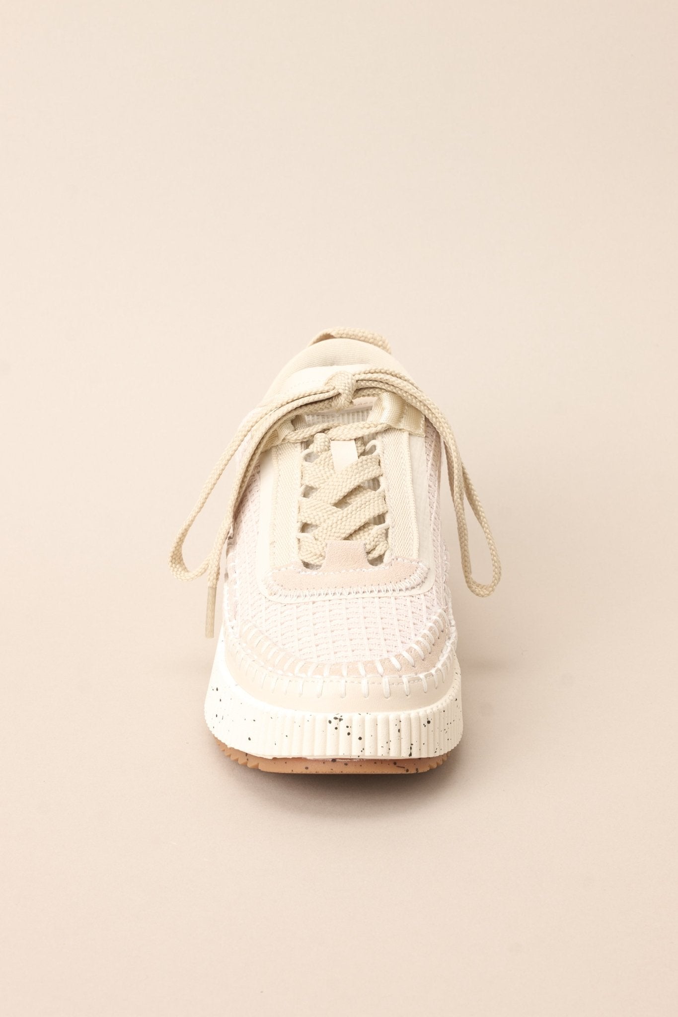 Front view of these beige sneakers with rounded toe, functional laces, knitted detailing, comfortable fit, thick speckled sole.