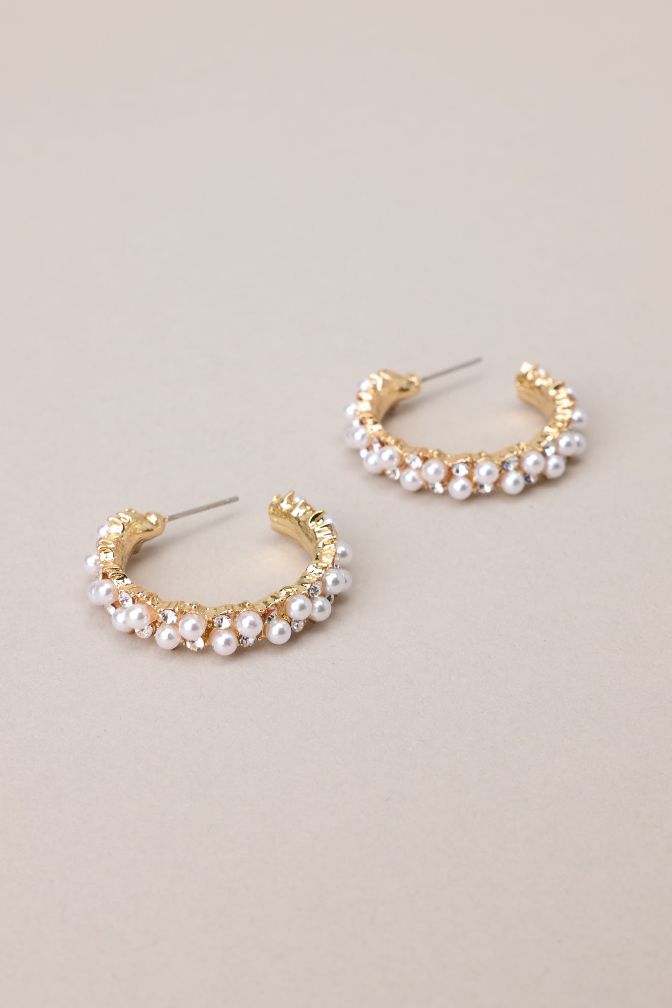 Close up view of these elegant earrings adorned with gold hardware, faux pearls, and shimmering rhinestones, complete with secure post backings for effortless wear.