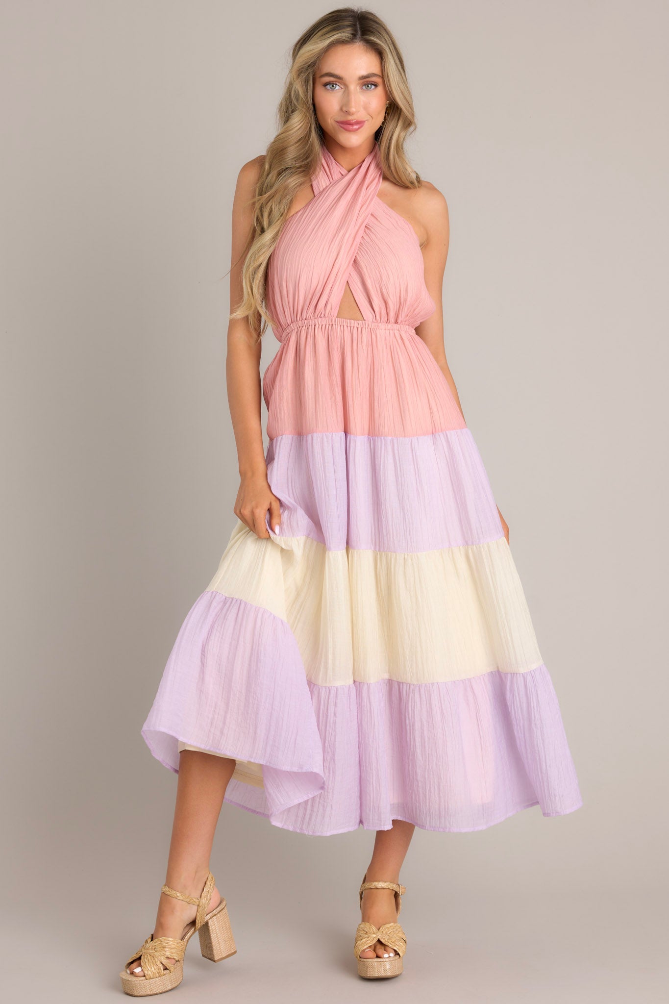 Full body view of this Pink dress featuring a self-tie halter neckline with a back tie closure, an alluring open back, an elastic band at the back of the bust for a comfortable fit, an elastic waistband, and a flowing skirt.