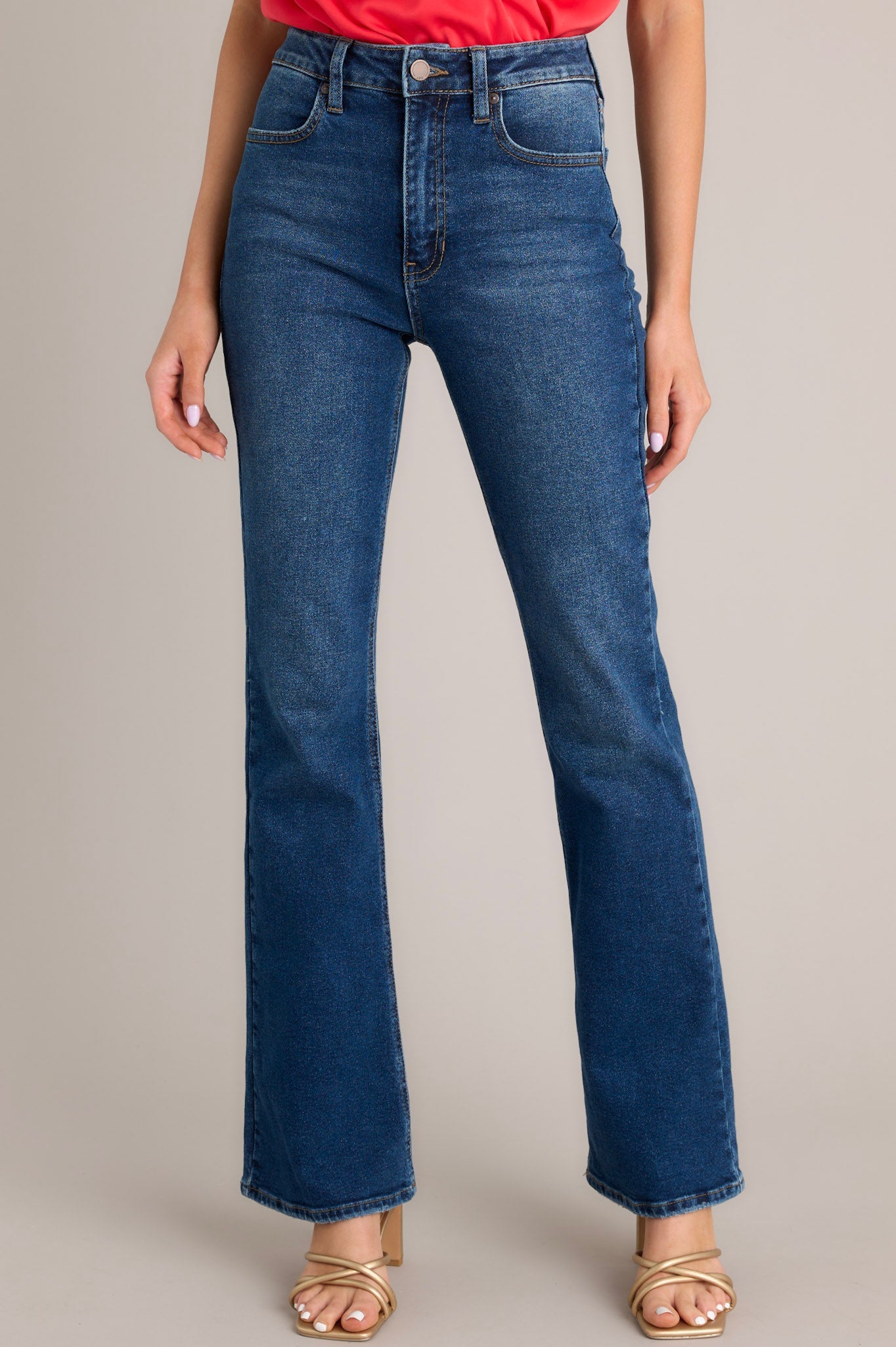 Front view of jeans featuring a high waisted fit, functional pockets on the front and back, belt loops, a zipper and button closure, and a flared out style.