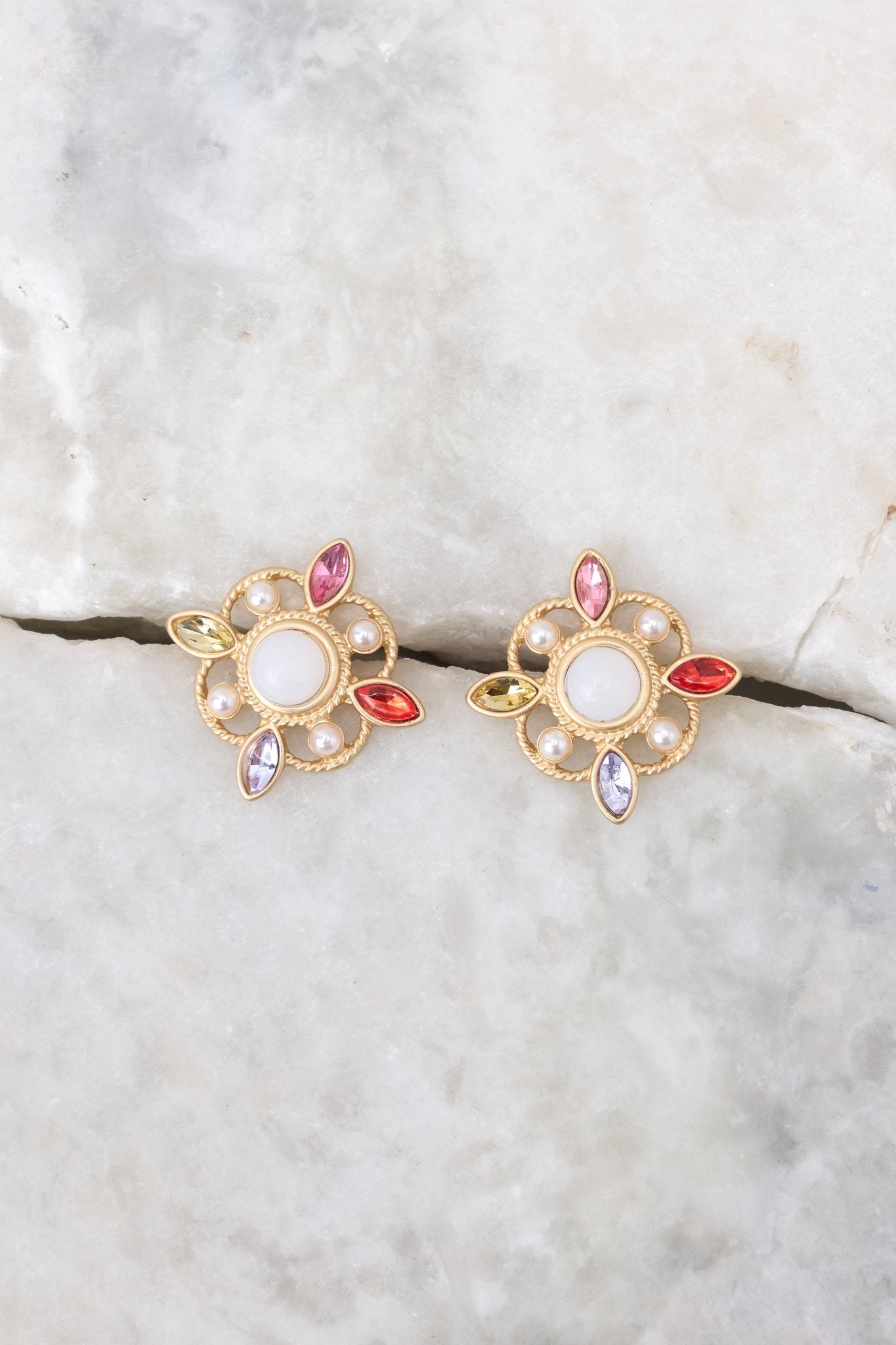 Overhead view of these earrings featuring gold hardware, pearl and rhinestone detailing, and a secure post backing