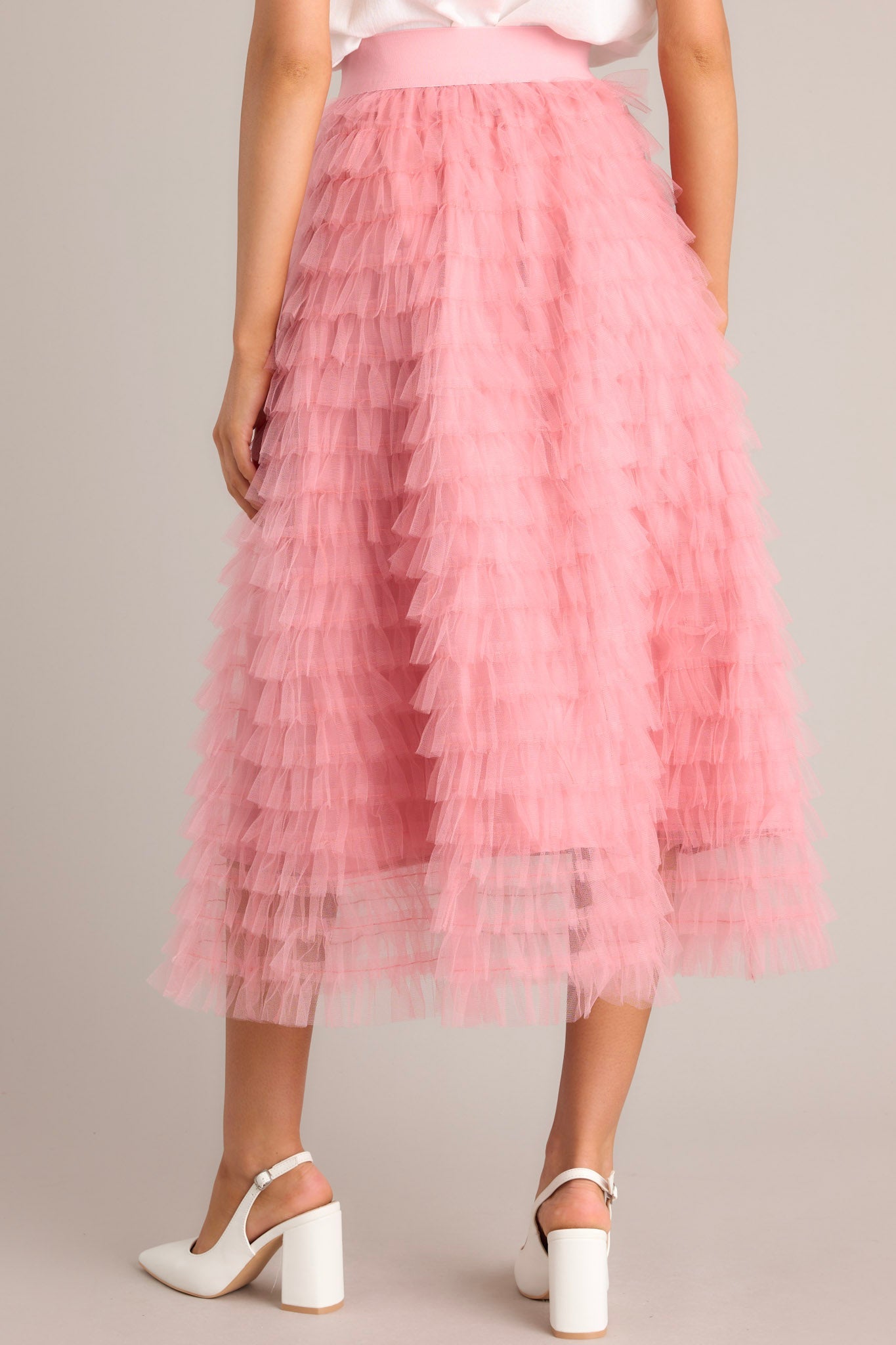 Back view of this pink skirt that features a high-waist design with an elastic waistband for a comfortable fit, adorned with charming ruffle tulle detailing throughout.