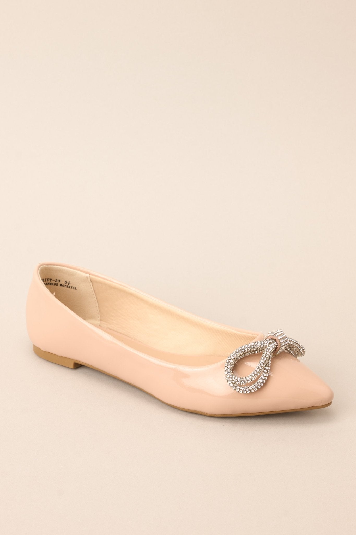 Angled front view of these chic flats with a pointed toe, adorned with a dazzling rhinestone-embellished bow, and finished with a shiny sheen.