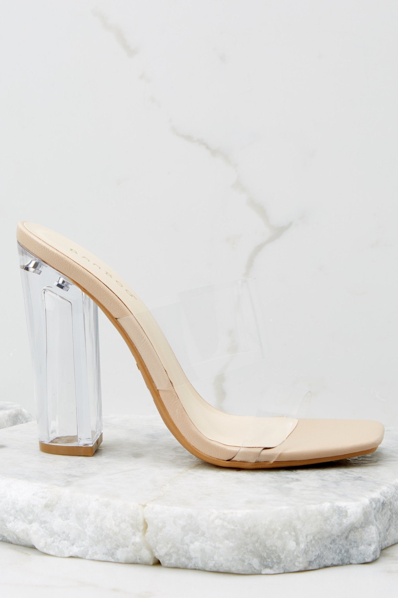 A zoomed-in shot of the clear block heel, emphasizing its sturdy yet modern design alongside the square toe and clear straps.