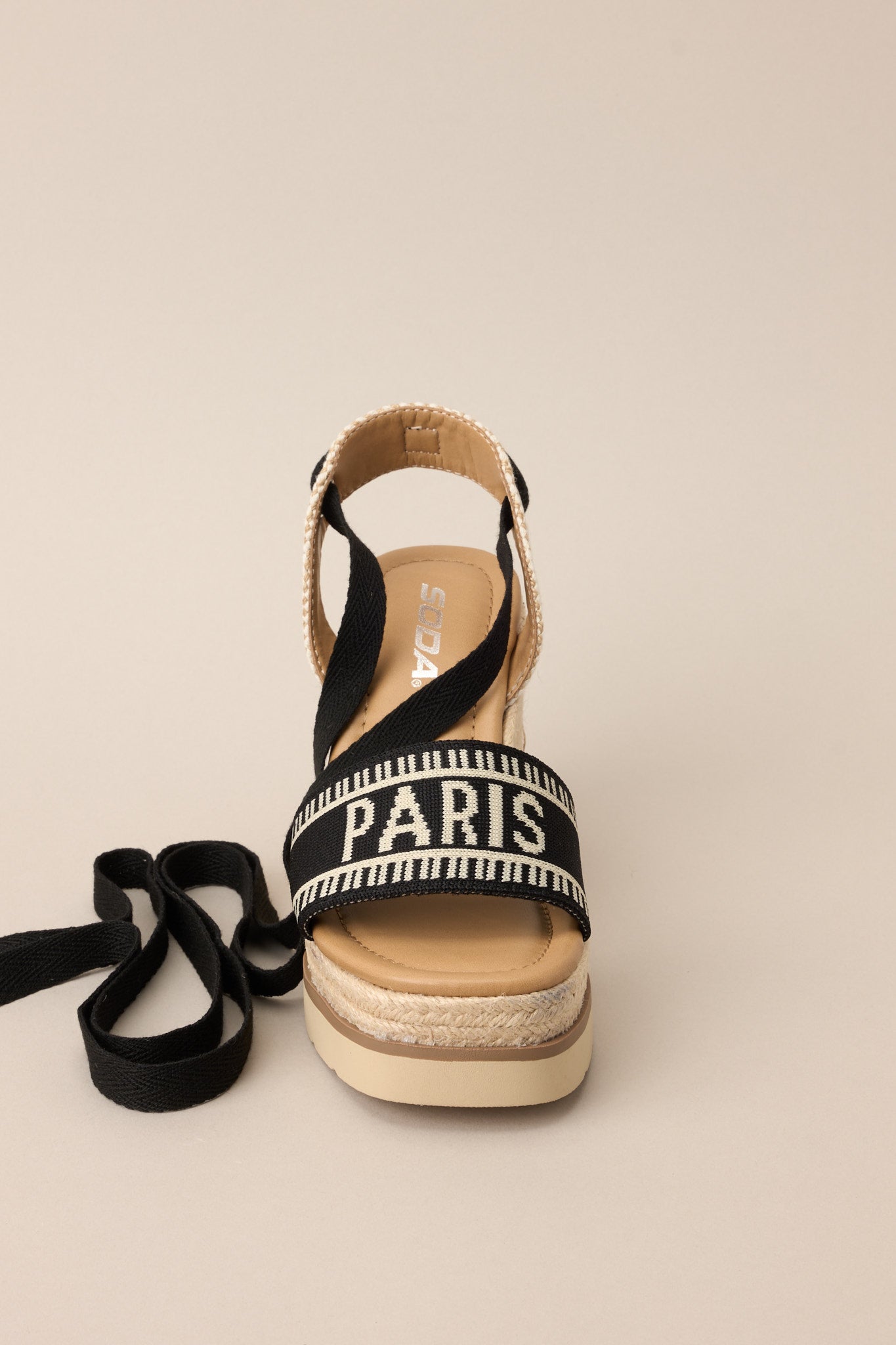 Front view of these black platform wedge sandals that feature a rounded toe, a strap over the top of the foot and around the heel, adjustable self-tie straps around the ankle, and a wedged heel.