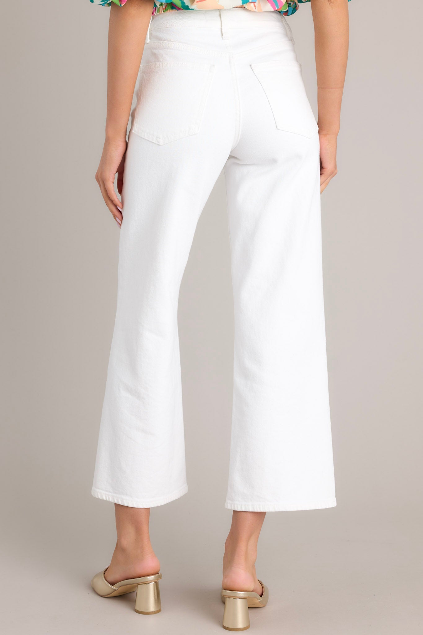 Back view of these white jeans that feature a high waisted design, classic button & zipper closure, belt loops, functional front & back pockets, and a cropped length.