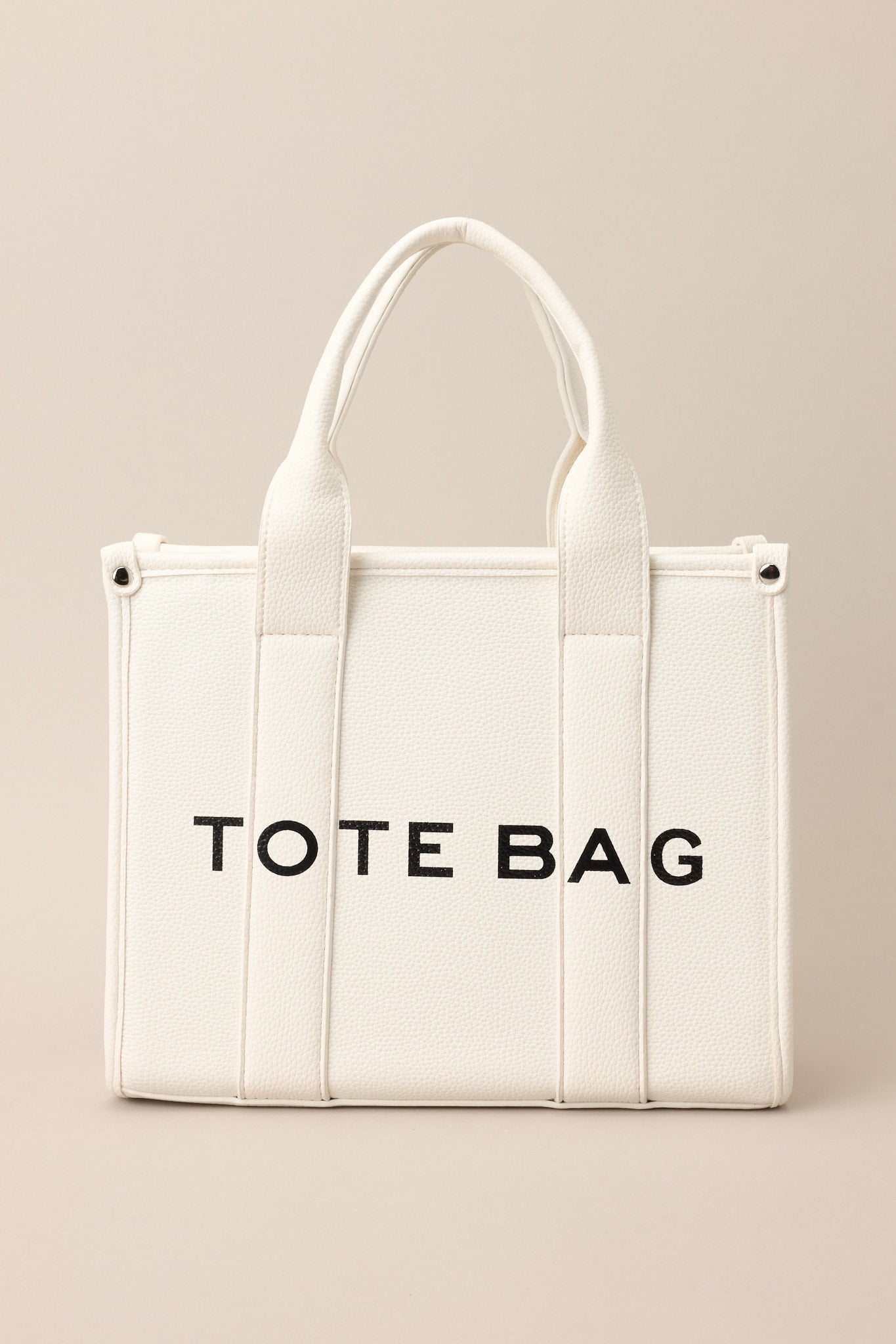 Full length view of a bag with silver hardware, top handles, a functional zipper closure, an additional pocket on the inside, and a removable strap