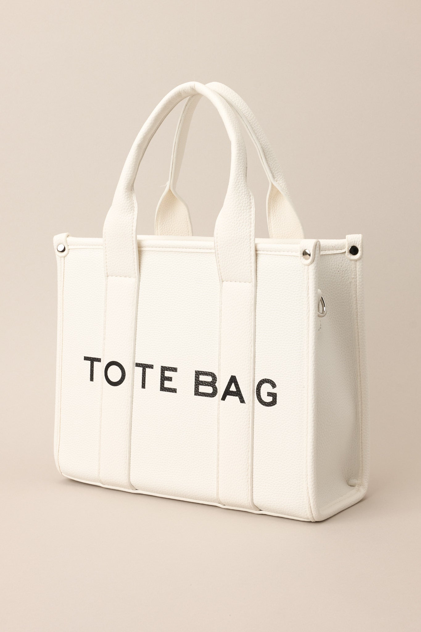 Front angled view of a bag featuring silver hardware, top handles, a functional zipper closure, an additional pocket on the inside, and a removable strap