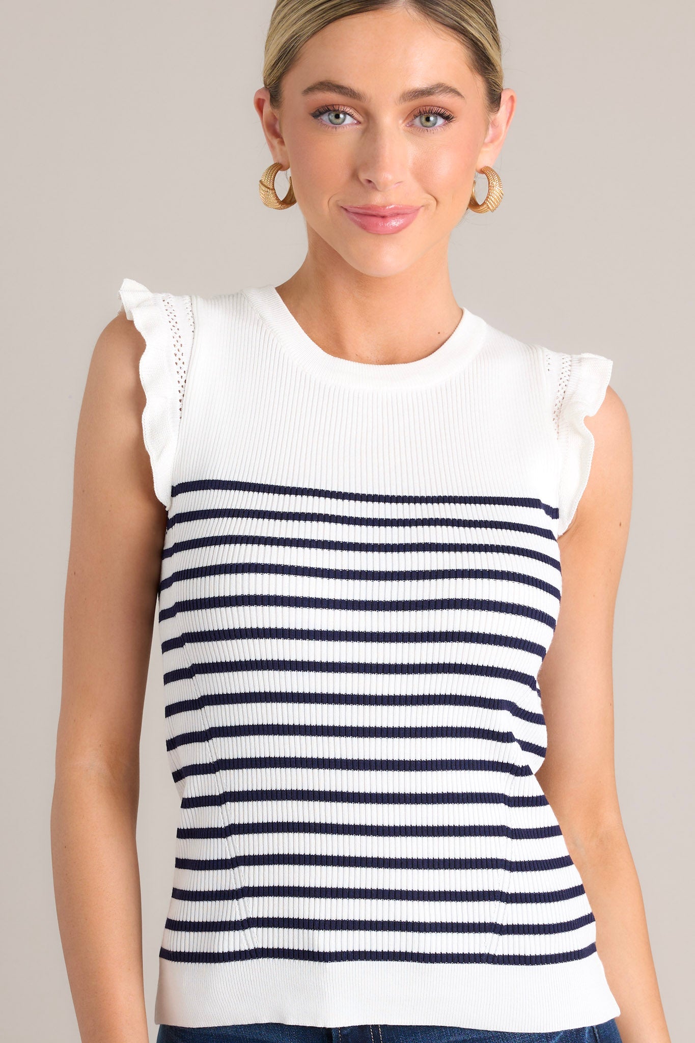 Front view of a white & navy striped top featuring a ribbed crew neckline, horizontal stripes, a stretchy knit fabric, and flutter sleeves.
