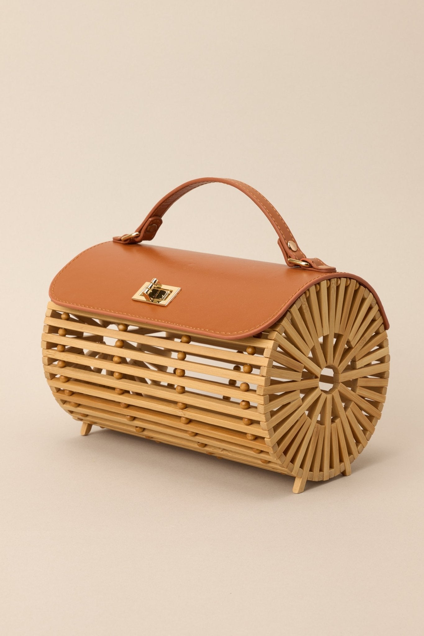 Side view of this bamboo handbag that features a top handle, a single flap design, a twist lock closure, and a removable chain strap.