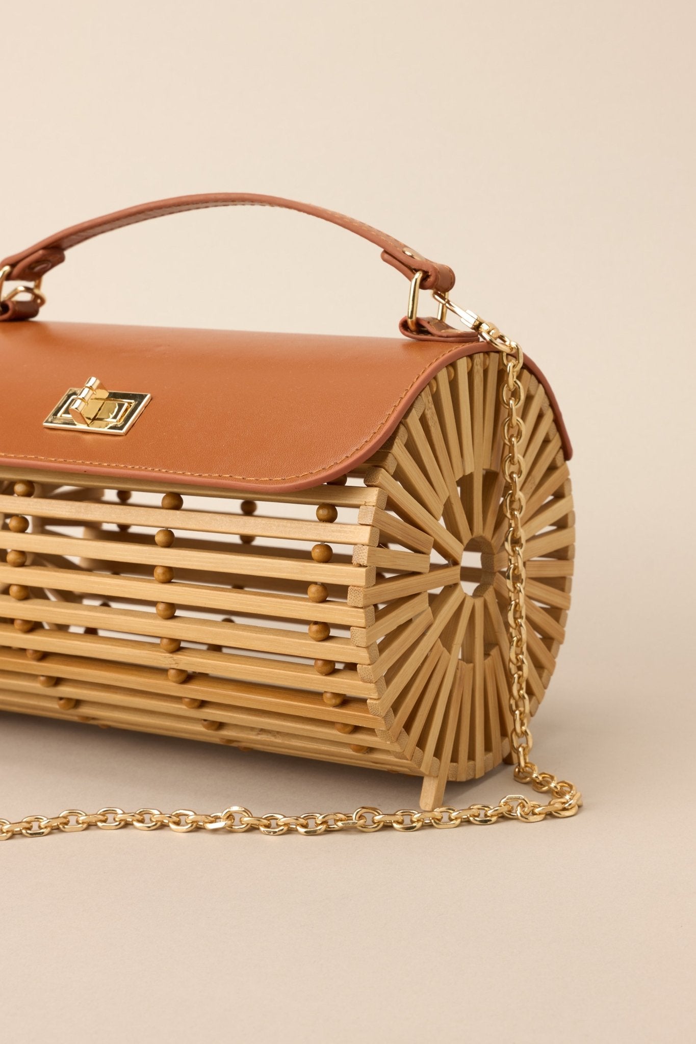 Side view of this bamboo handbag that features a top handle, a single flap design, a twist lock closure, and a removable chain strap.