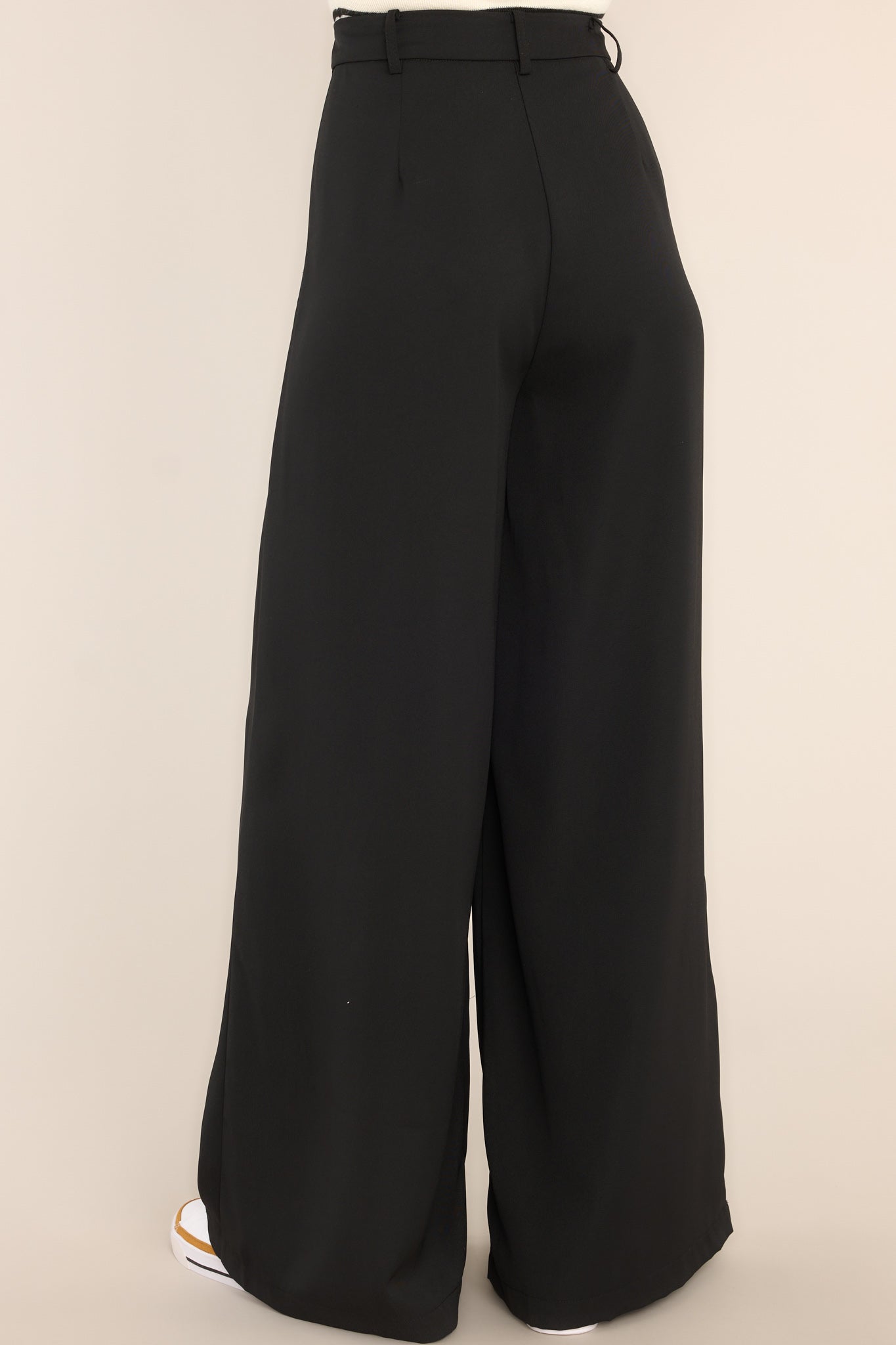 Back view of black pants featuring a high waist fit, belt loops, and pockets.