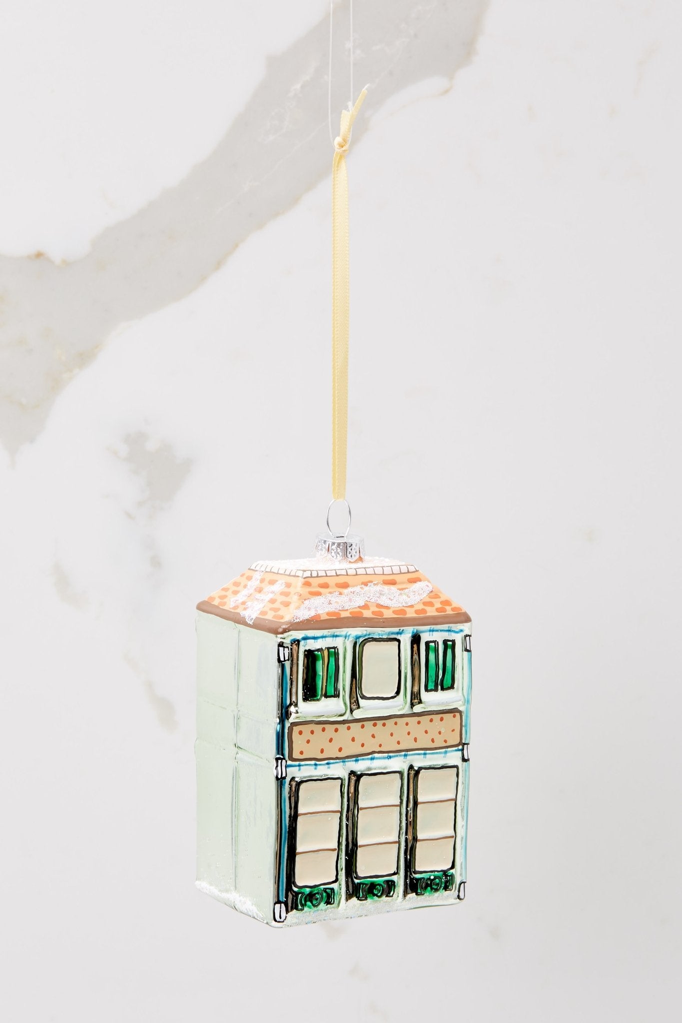 Back view of this ornament that features a building shape that says "BOOK SHOP" and has a cat in one of the windows.
