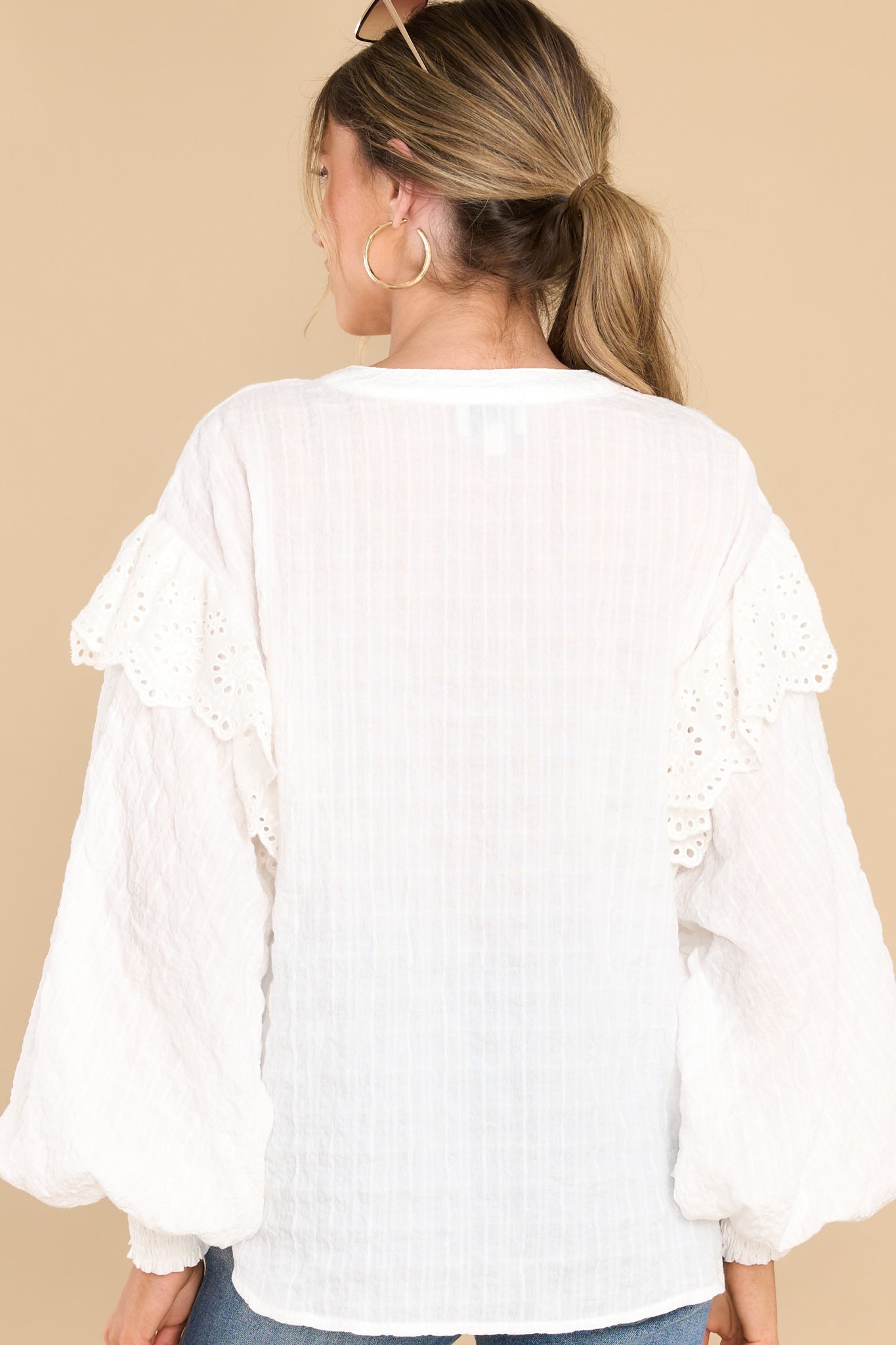 Back view of this top that features a high-neckline, buttons down the front, ruffle detail along the shoulders, puff sleeves with smock detailing at the cuffs, and a relaxed fit.