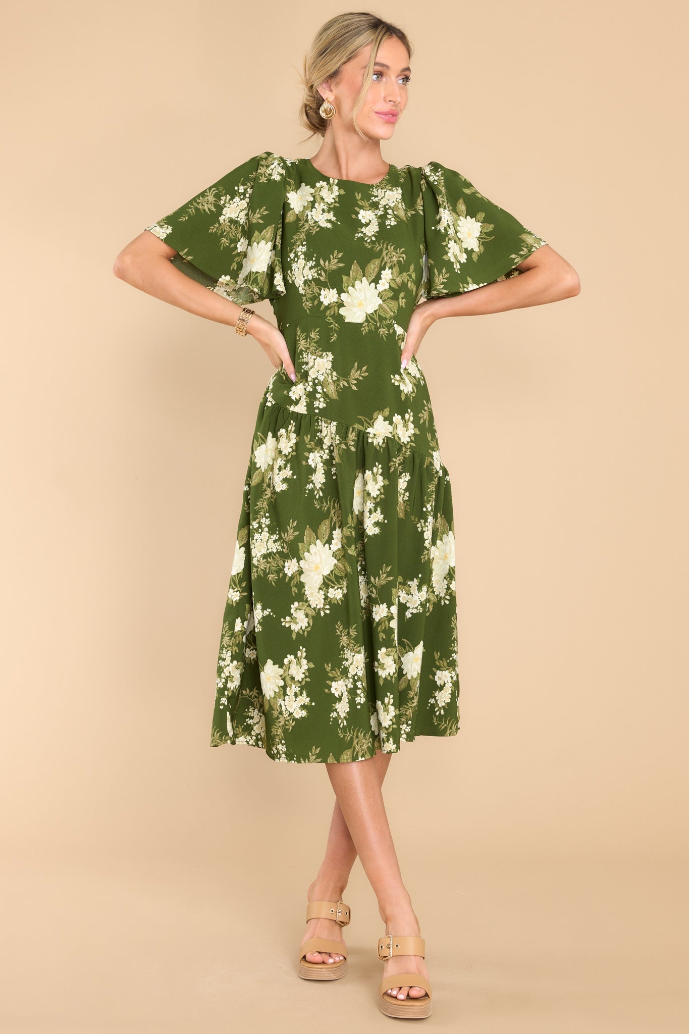 Front view of this dress that features a round neckline, butterfly sleeves, a keyhole cutout at the back of the neck with a button closure, a side zipper, and an asymmetrical detail along the waistline and hips.