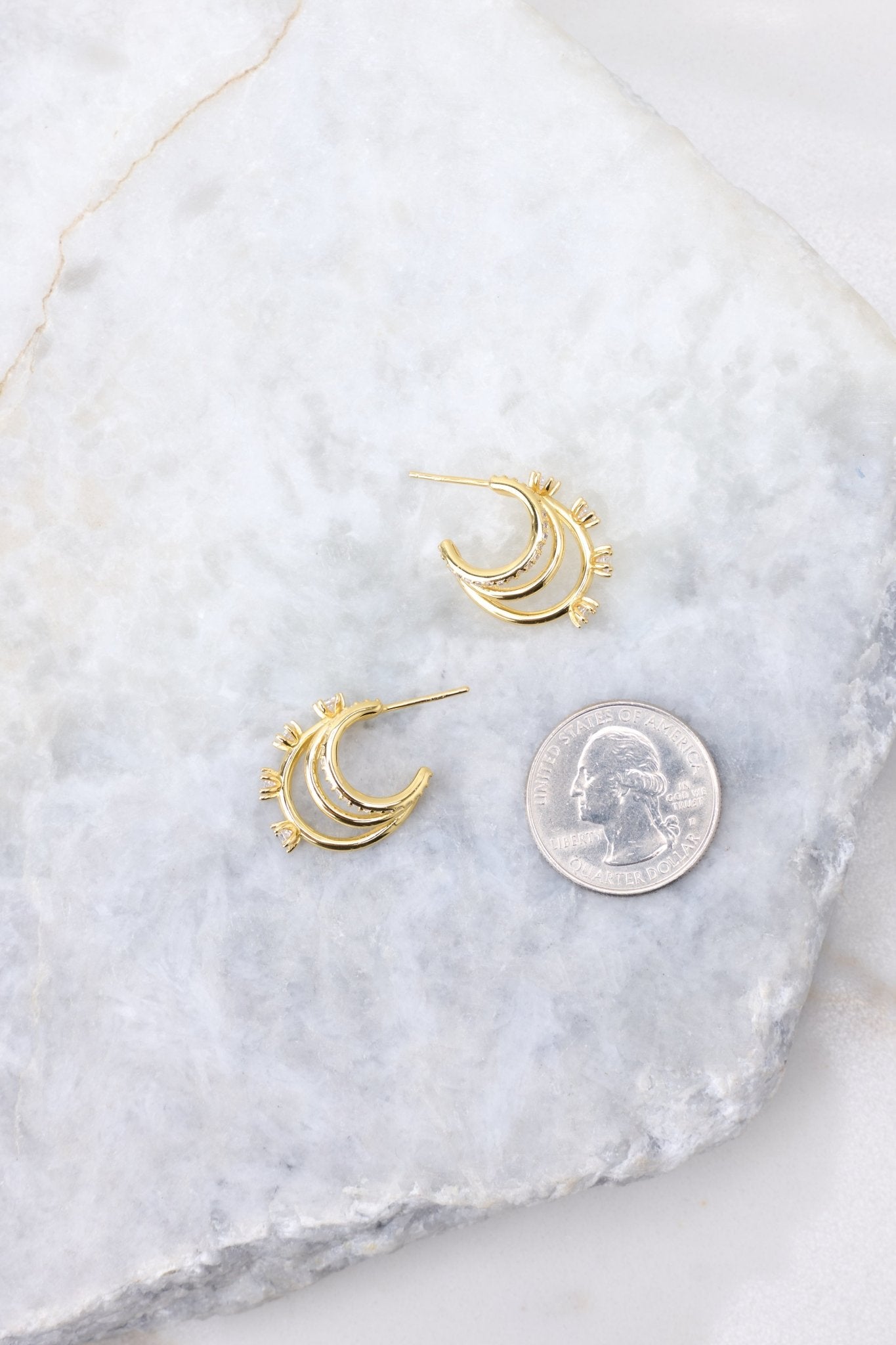 Gold huggie hoop earrings compared to quarter for actual size. Earrings measure .75" in length.