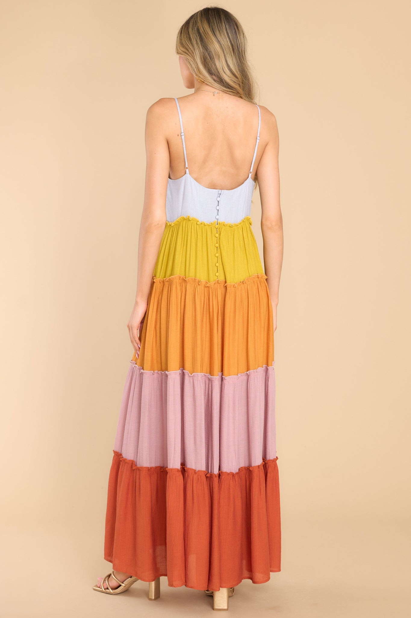 Back view of this dress that features a sweetheart neckline with ruffle detailing, thin adjustable shoulder straps, functional buttons for closure in the back of the bust, and a multicolored, tiered skirt with ruffle detailing.