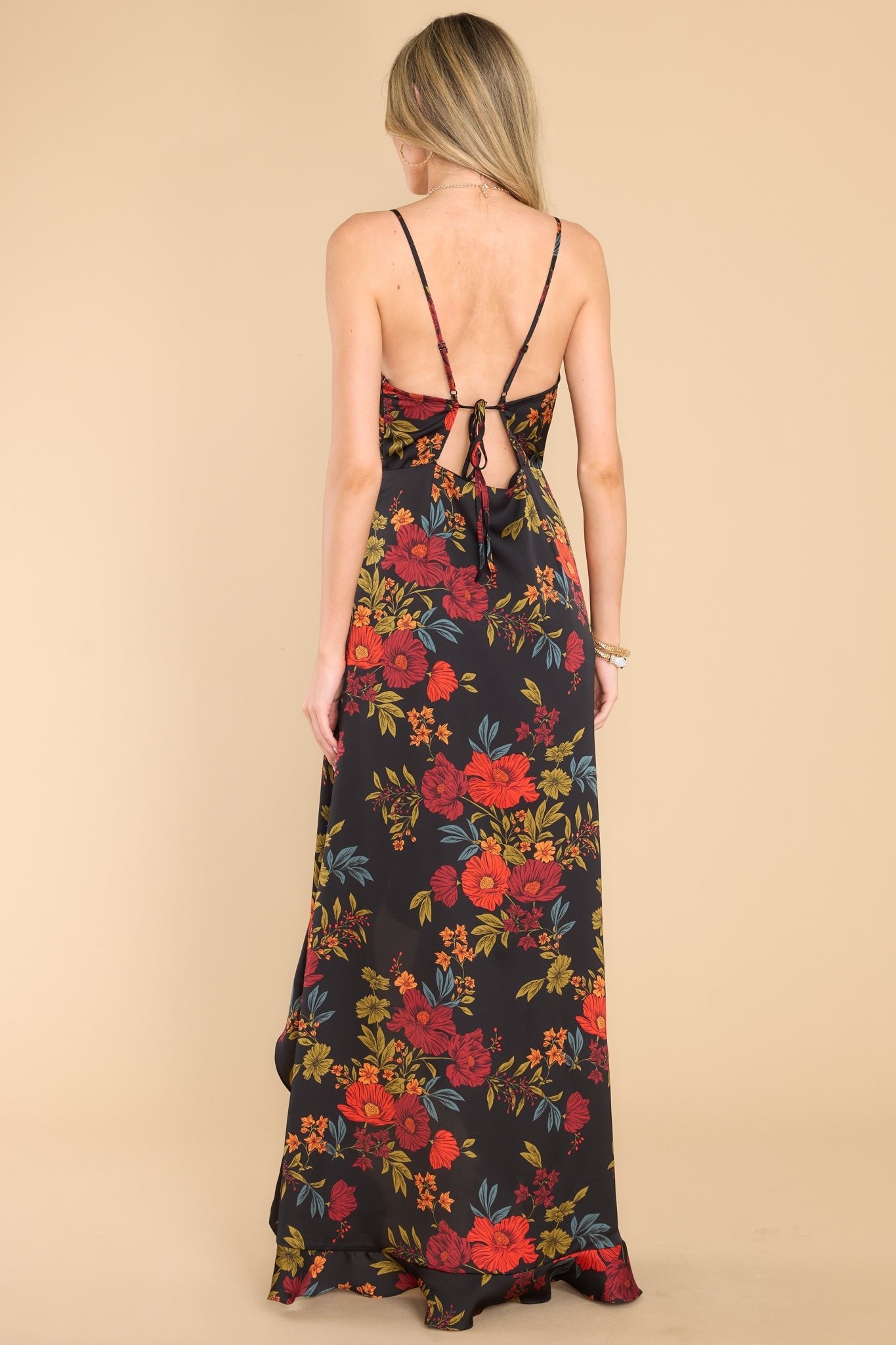 Back view of this dress that features a v-neckline with a snap button closure, adjustable straps, a self-tie in the back, a side zipper, ruffle detailing, and a wide slit up the leg.