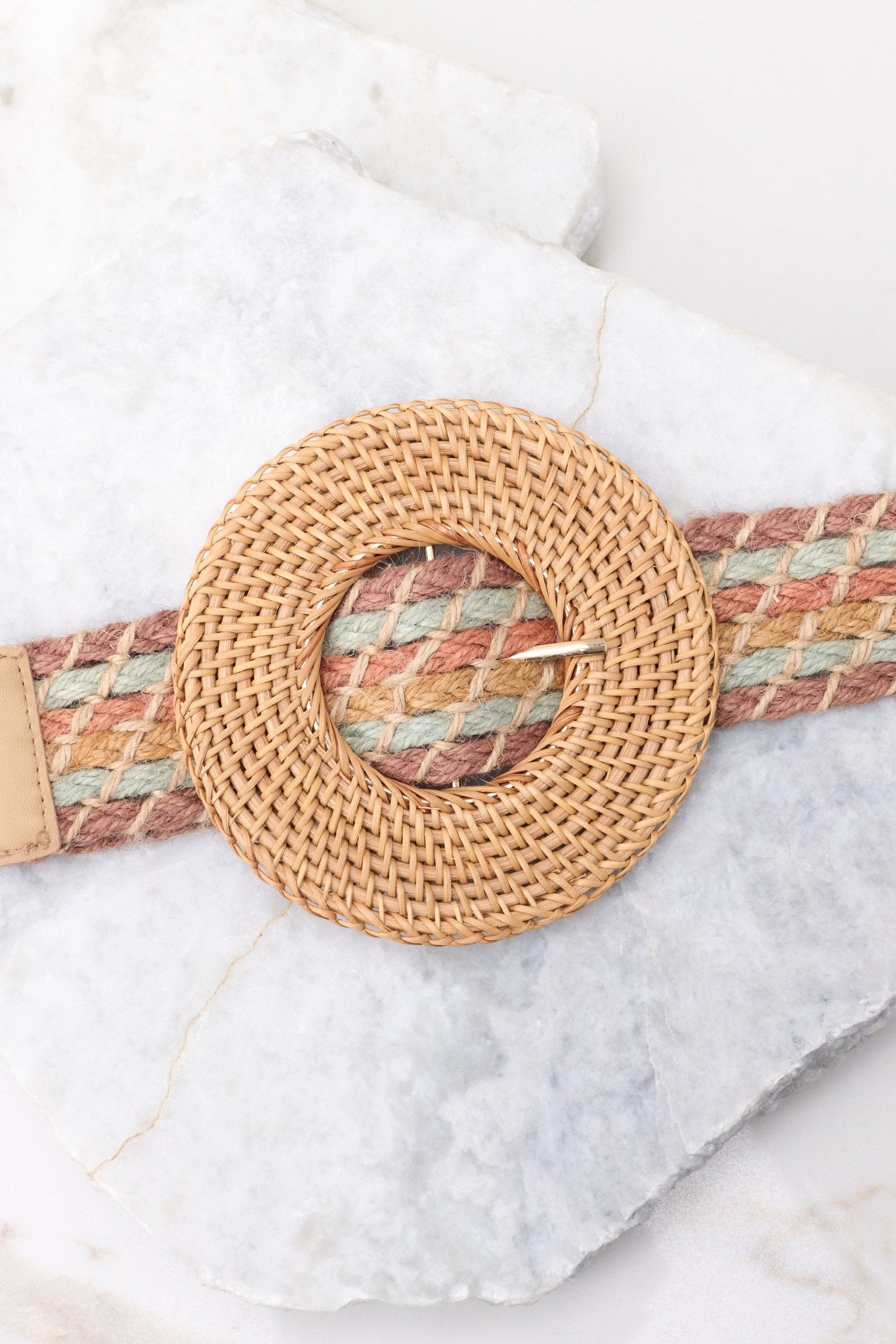 Close up view of this belt that features a circular belt buckle, and a woven material.