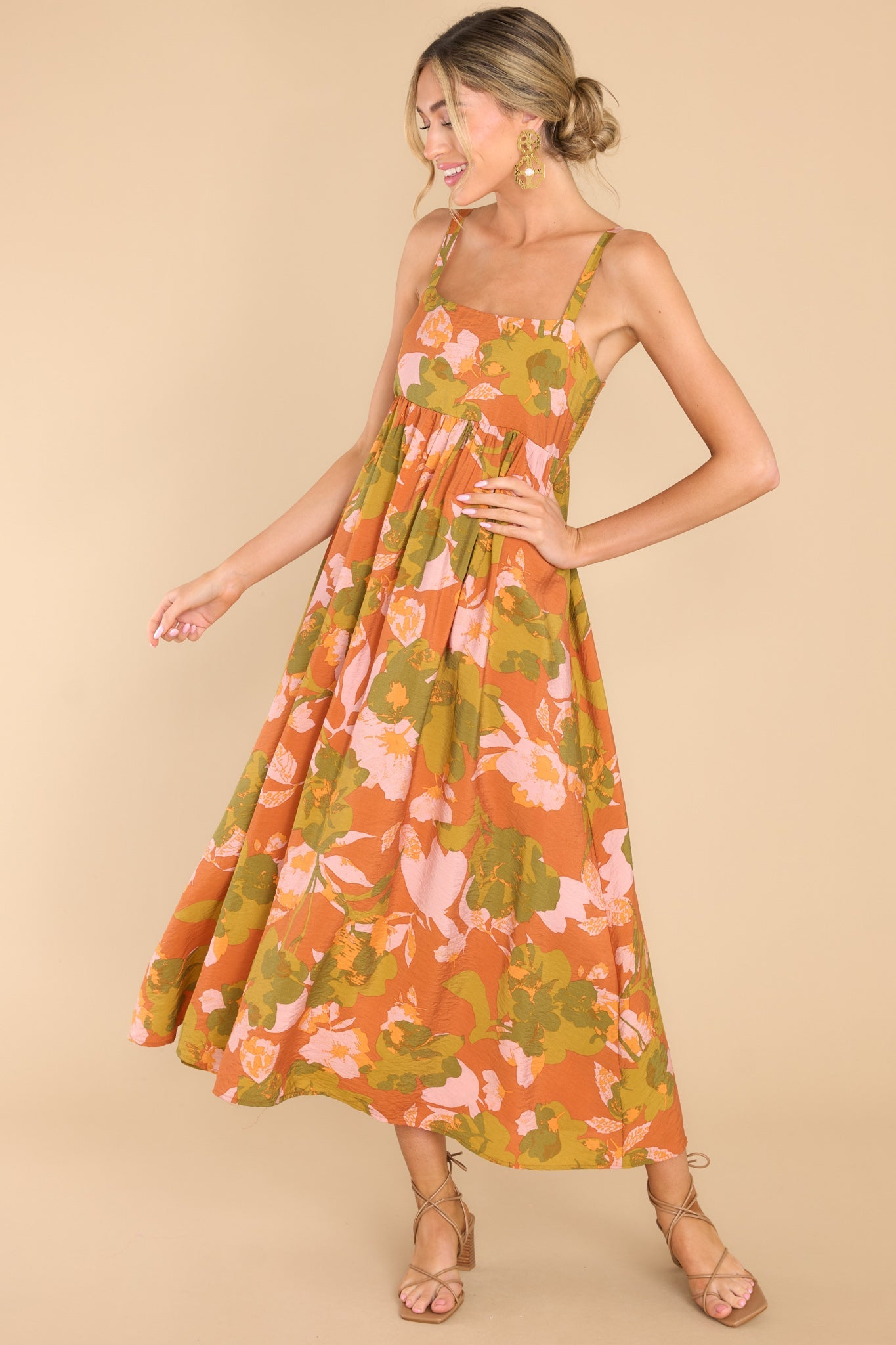 Full body view of this dress that features a square neckline, thin adjustable shoulder straps, a babydoll silhouette, a smocked section in the back of the bodice, and a flowy skirt.