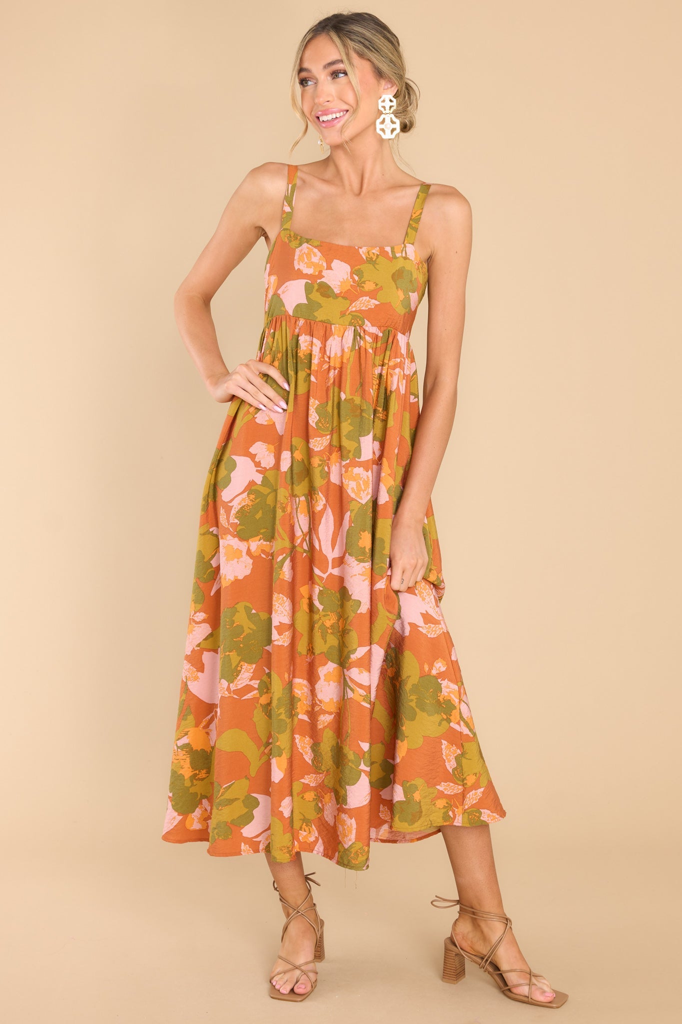 Front view of this dress that features a square neckline, thin adjustable shoulder straps, a babydoll silhouette, a smocked section in the back of the bodice, and a flowy skirt.