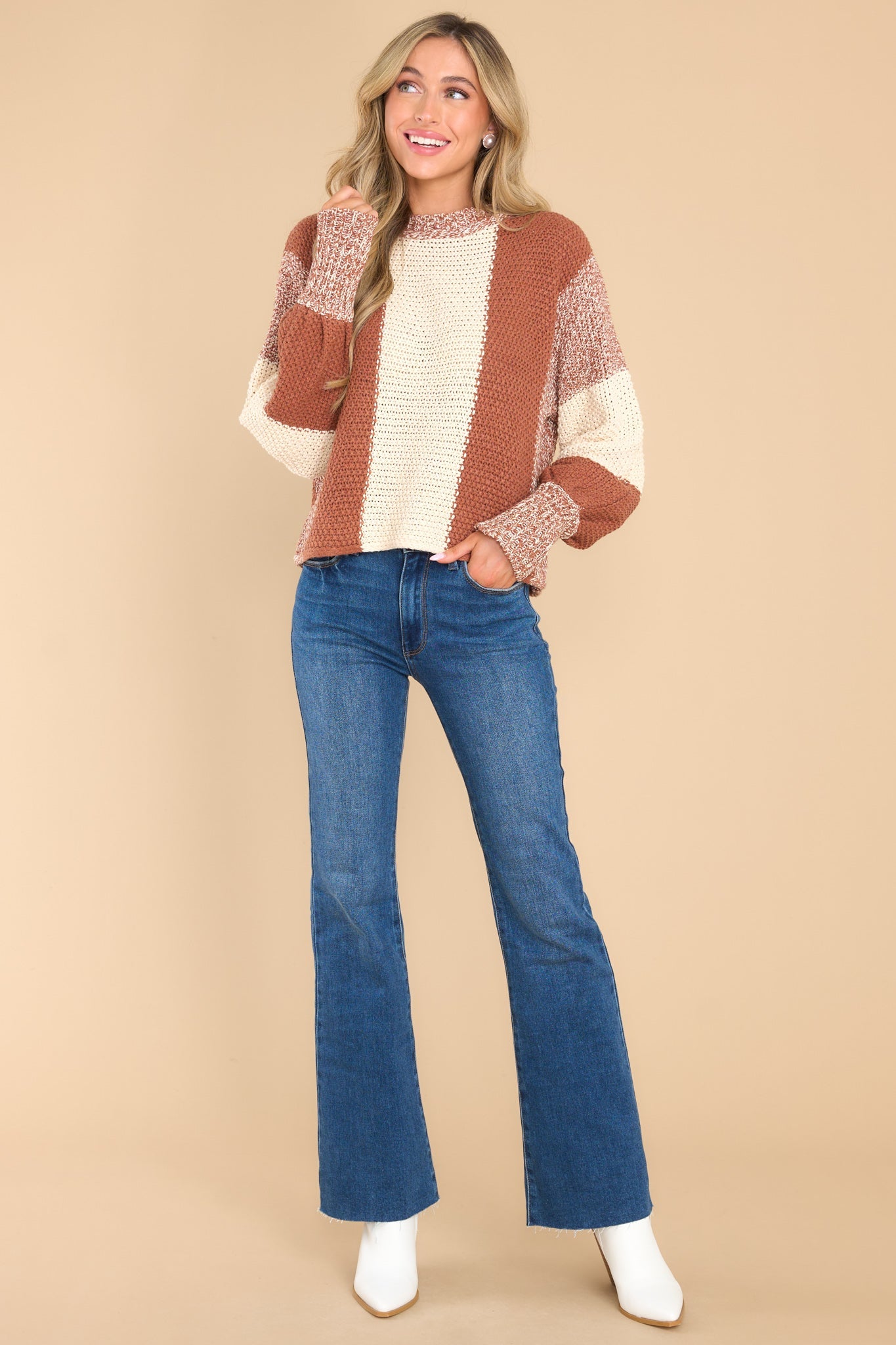 Full body view of this sweater that features a round neckline, long sleeves with stretchy cuffs, a chunky knit texture, and a striped colorblock design.