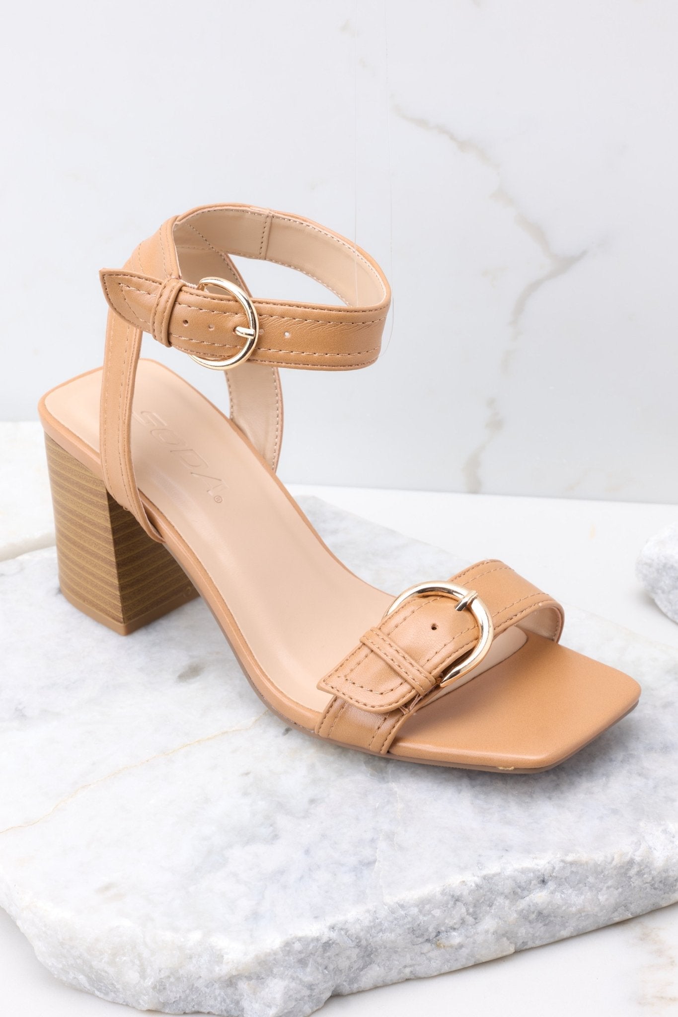 Close up view of these heels that feature an adjustable ankle strap, a buckle design on the top of the toes, and a block heel. 