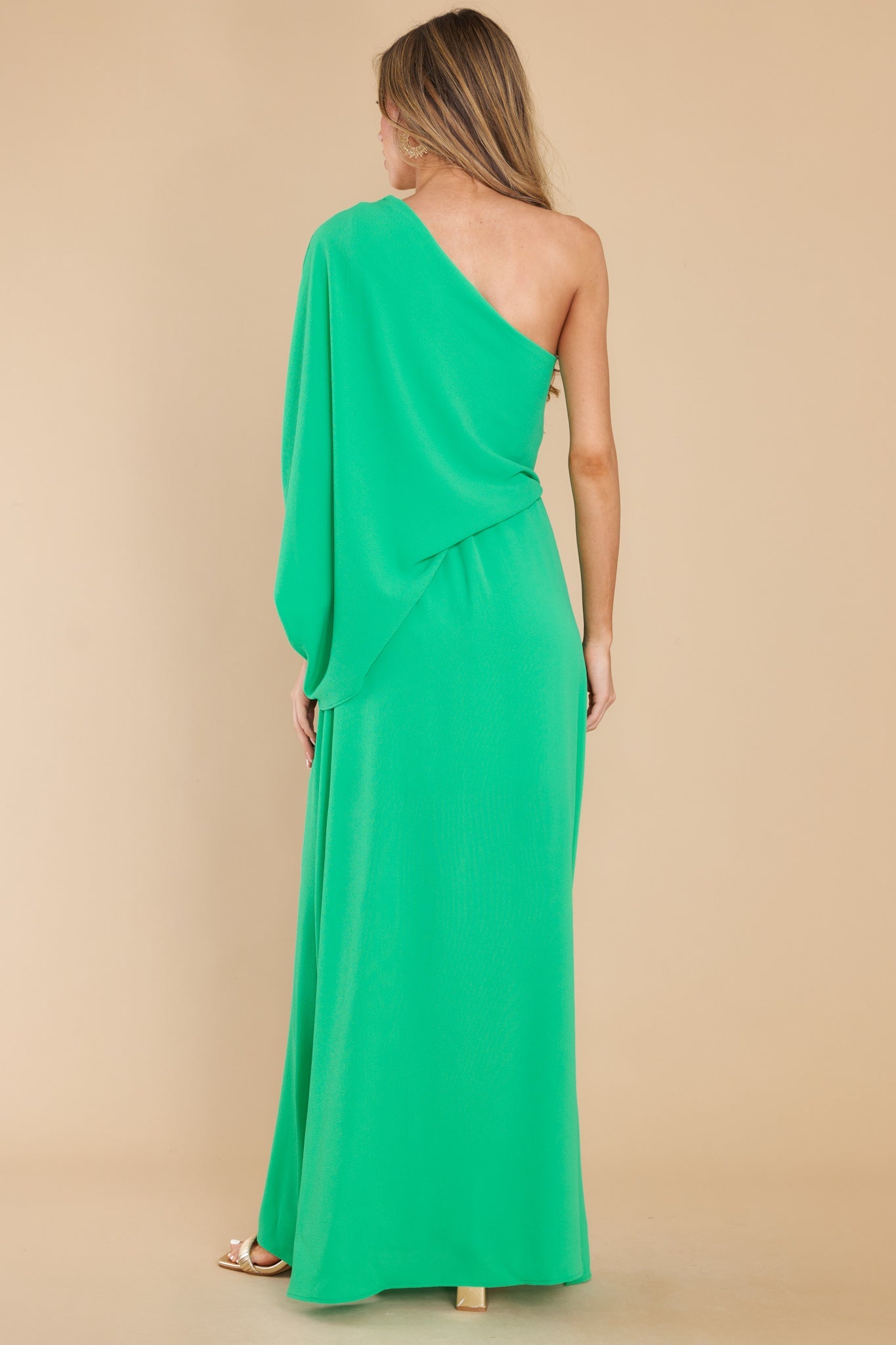 Back view of this dress that features an off the shoulder neckline, large dolman sleeve, an elastic waistline, and an elegant side slit.