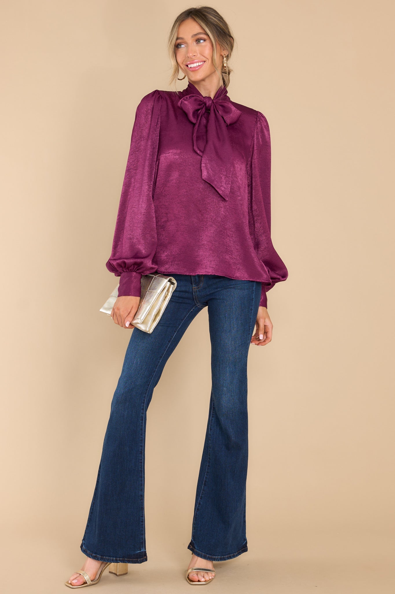 This dark berry top features a high neckline with an adjustable self tie, flowy balloon sleeves with two buttons at the cuff, and a relaxed fit.