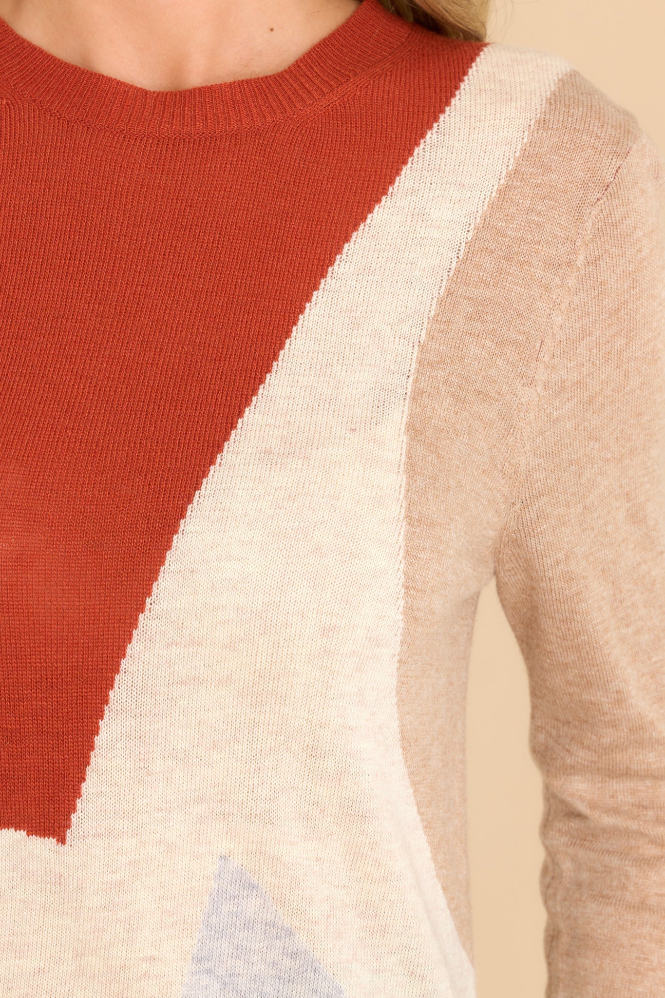 Close up view of this sweater that features a crew neckline, ribbed cuffs and hem, a multi-colored geometric pattern, and a soft knit material.