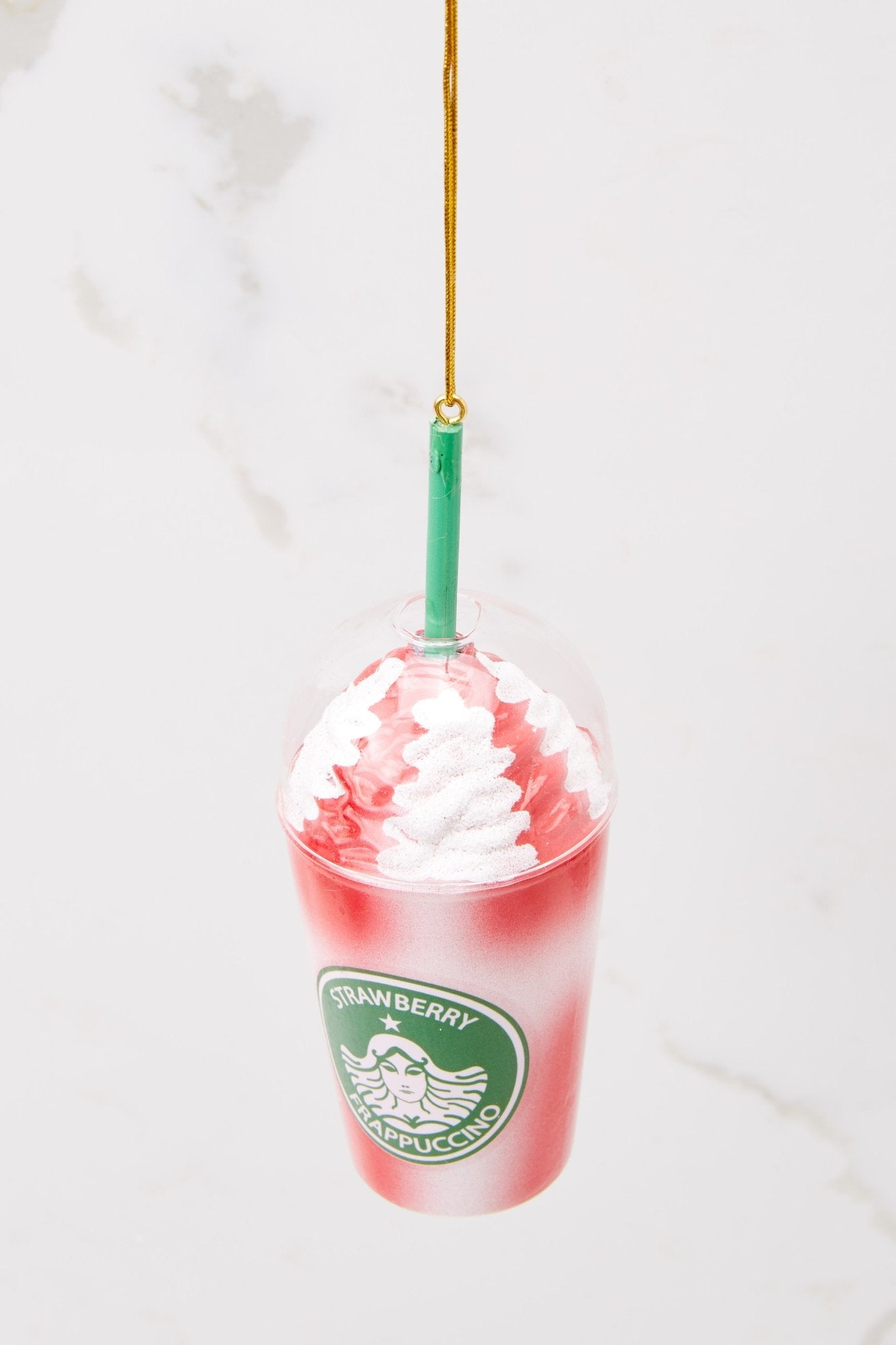 Top view of this ornament that features a "STRAWBERRY FRAPPUCCINO" with white and red cool whip on the top and a green straw.